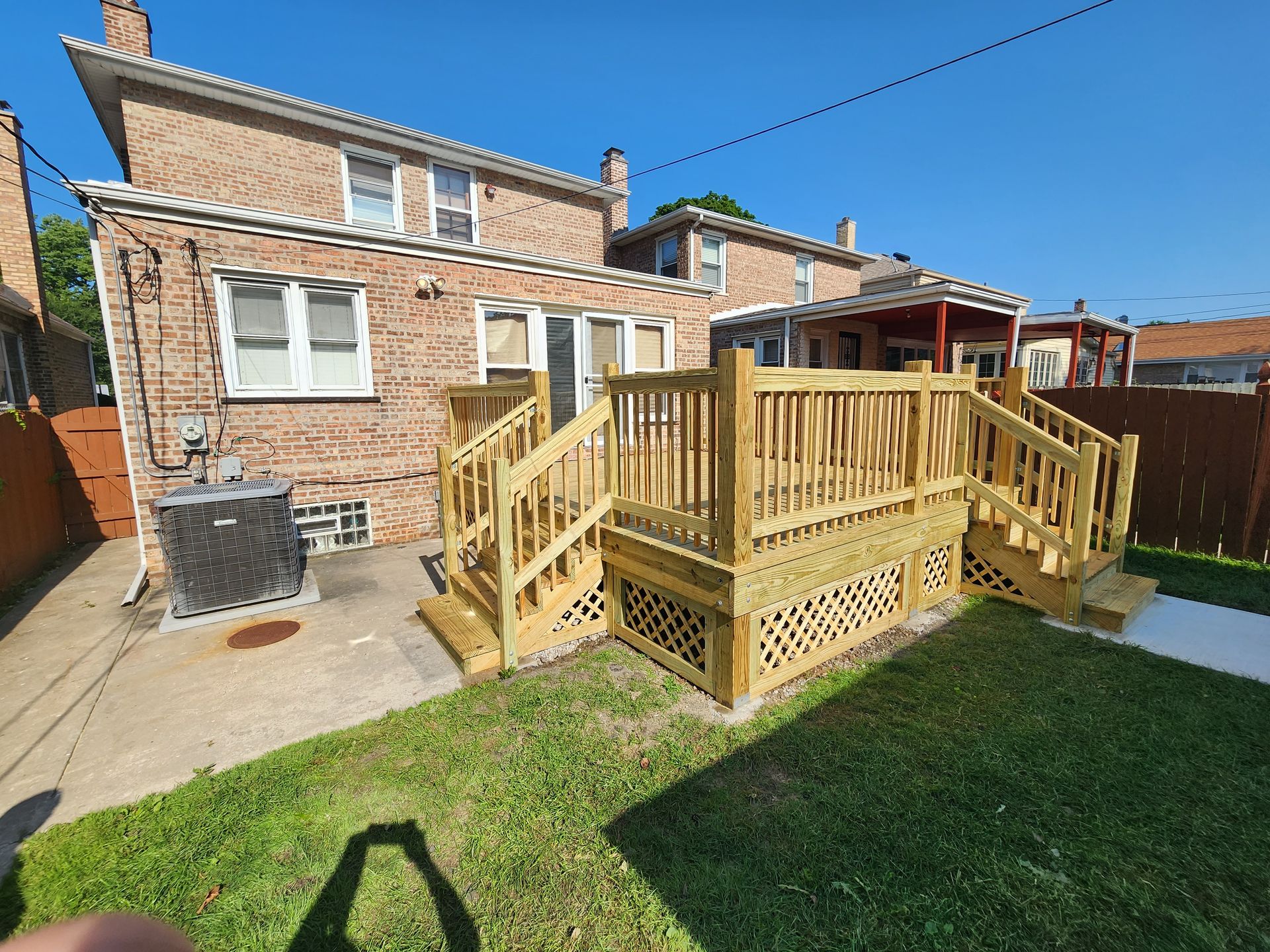 A wooden deck with stairs is in the backyard of a house.