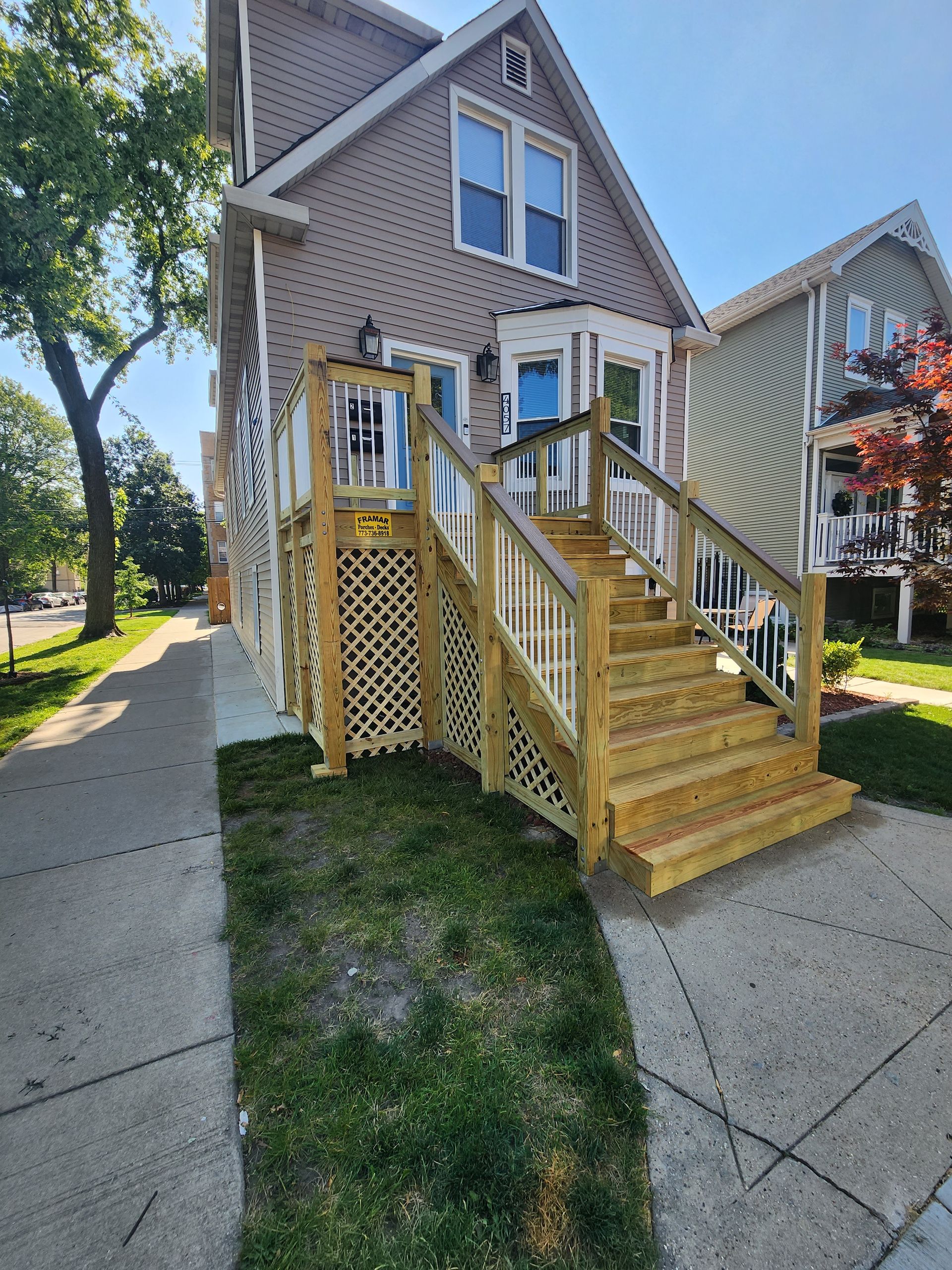 A house with a wooden deck and stairs in front of it.