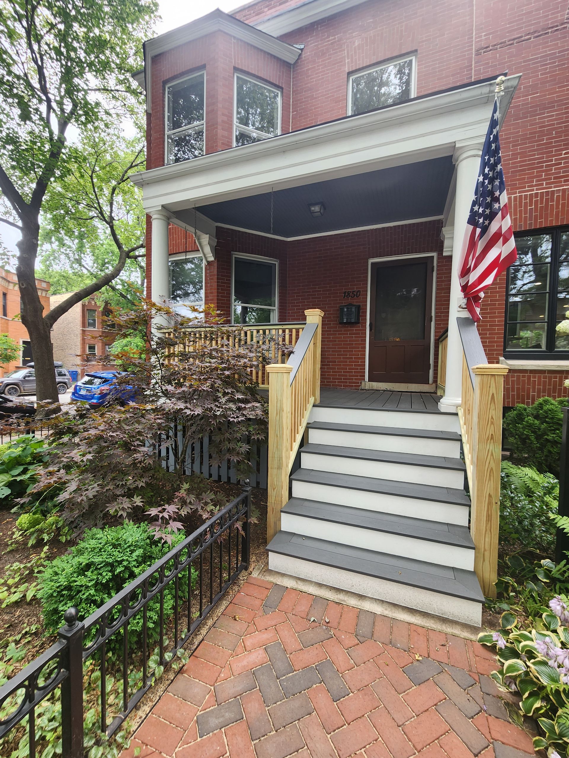 A brick house with a porch and stairs and an american flag