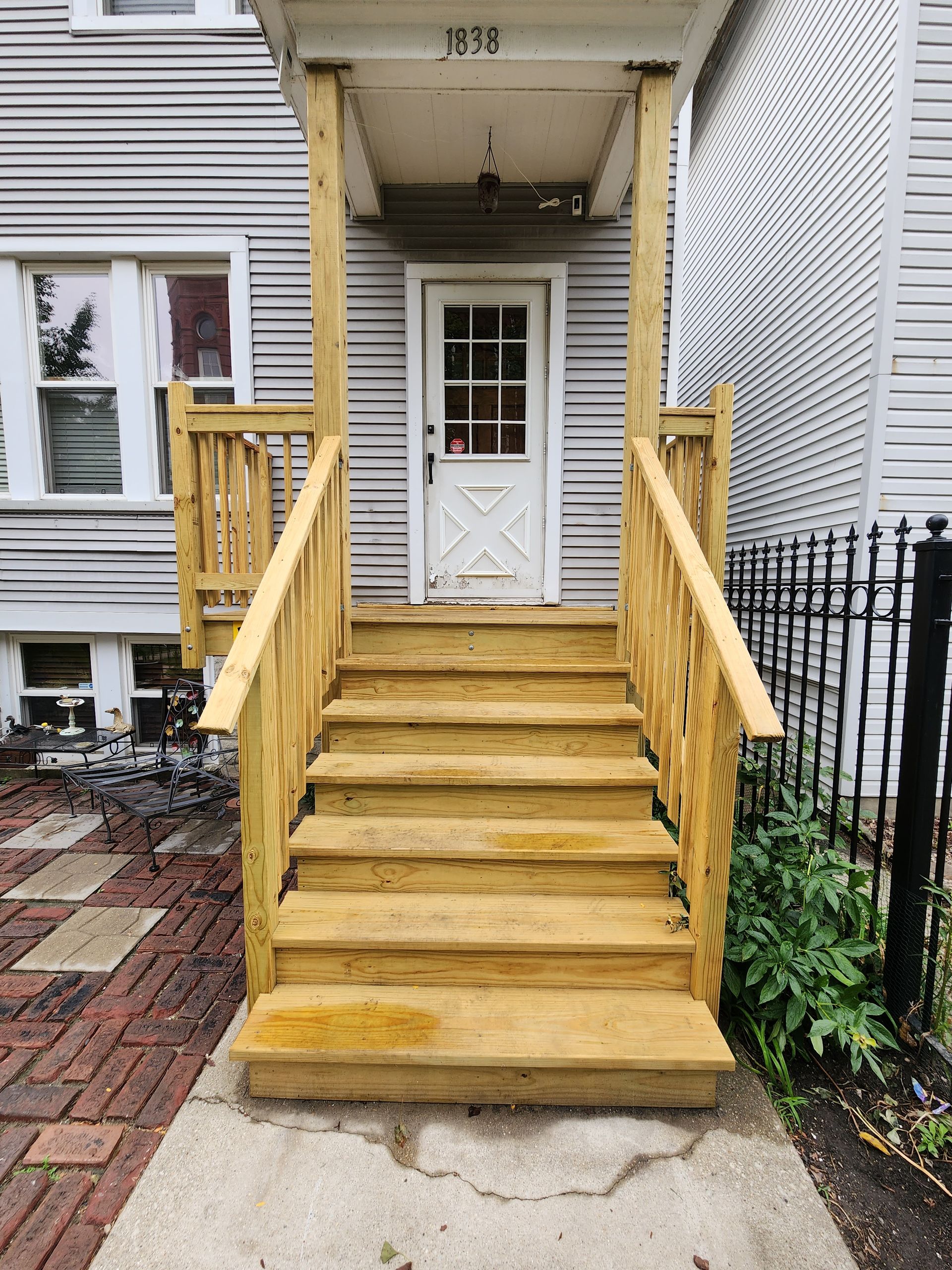 A wooden porch with stairs leading up to the front door of a house.