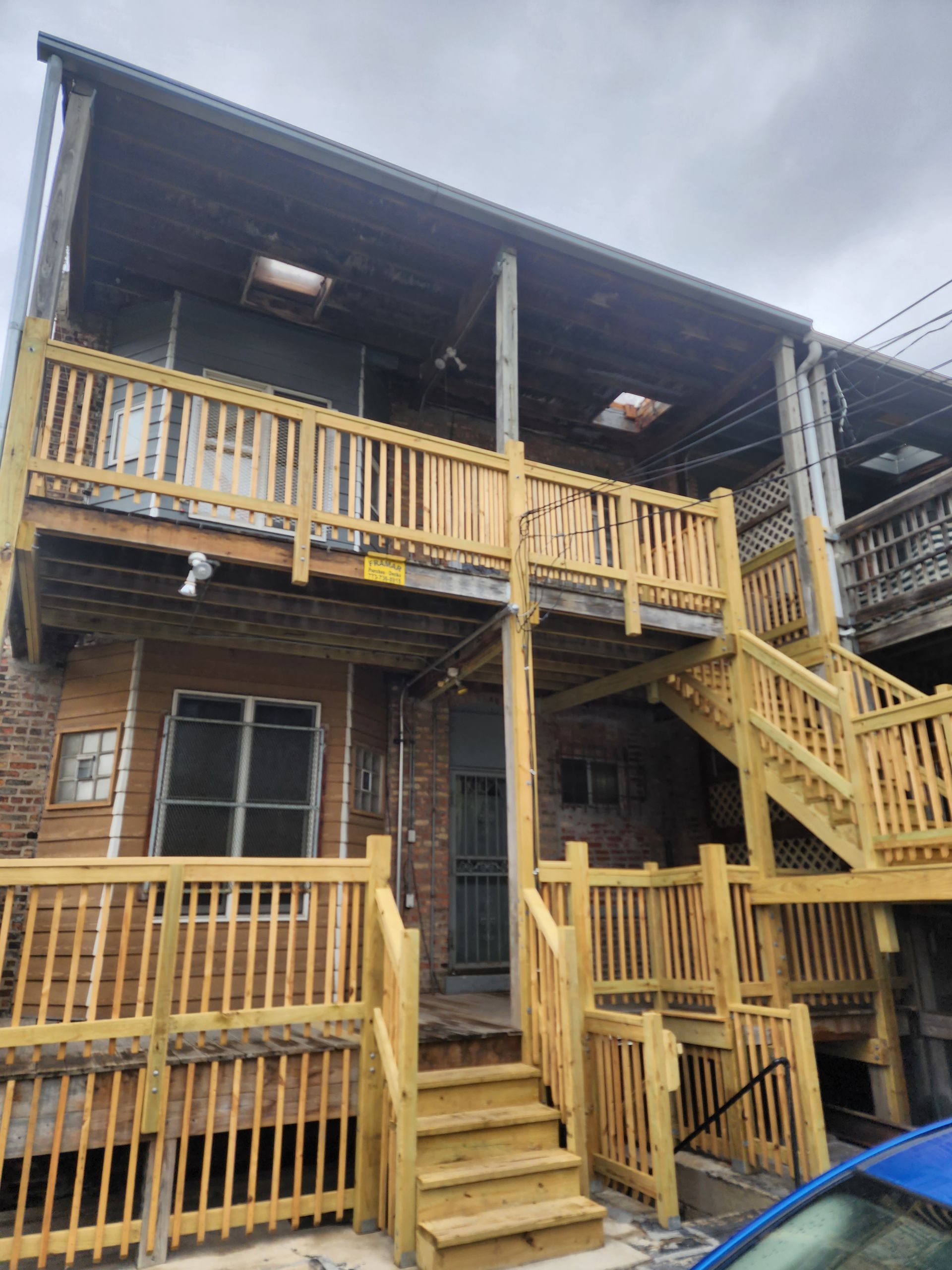 A wooden deck with stairs leading up to it is in the backyard of a house.