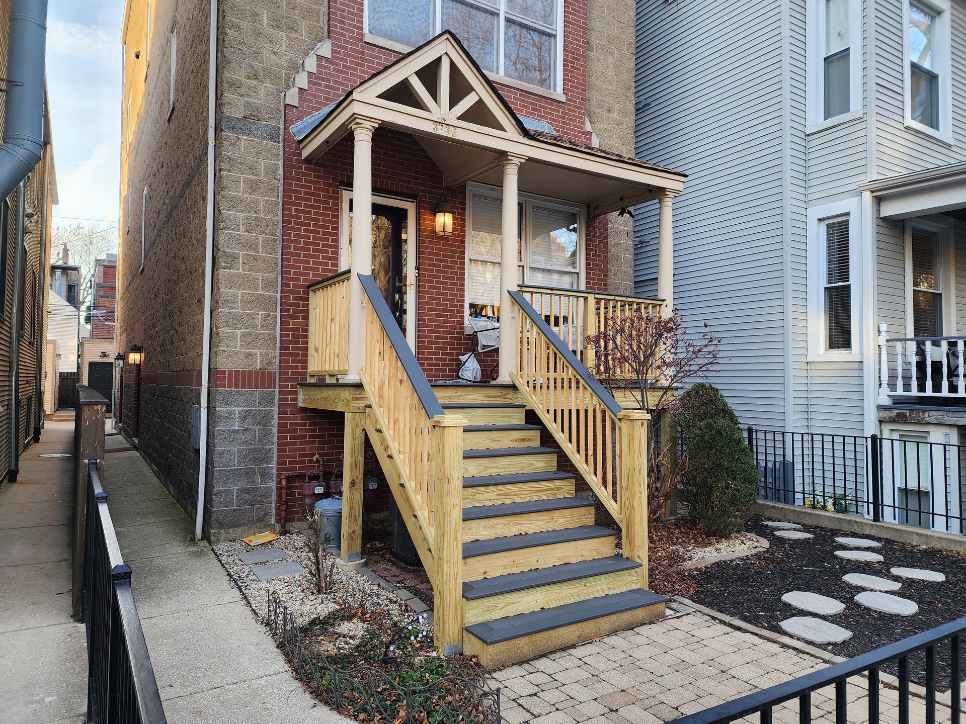 A brick house with a wooden porch and stairs.