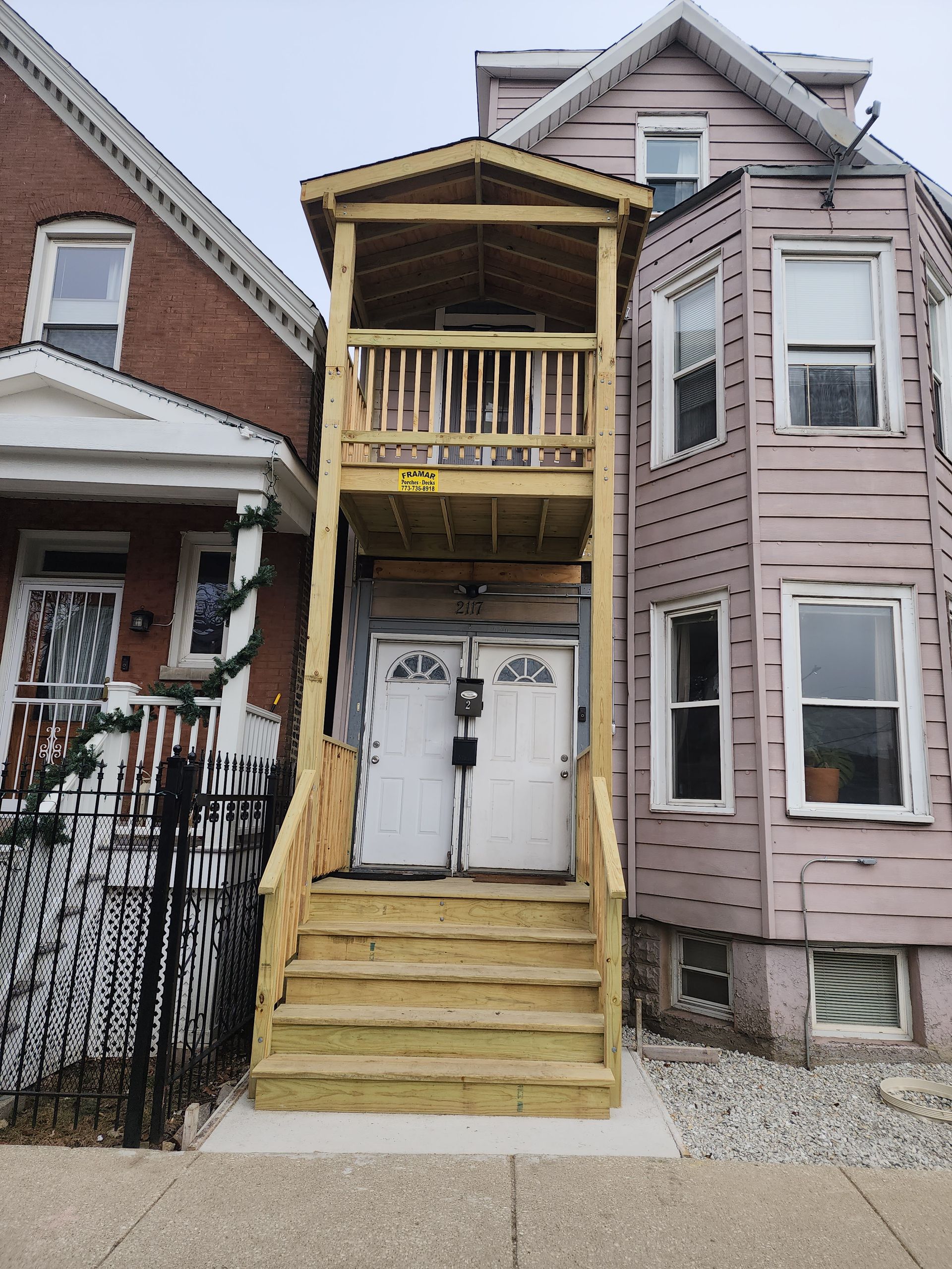 A pink house with a wooden deck and stairs.