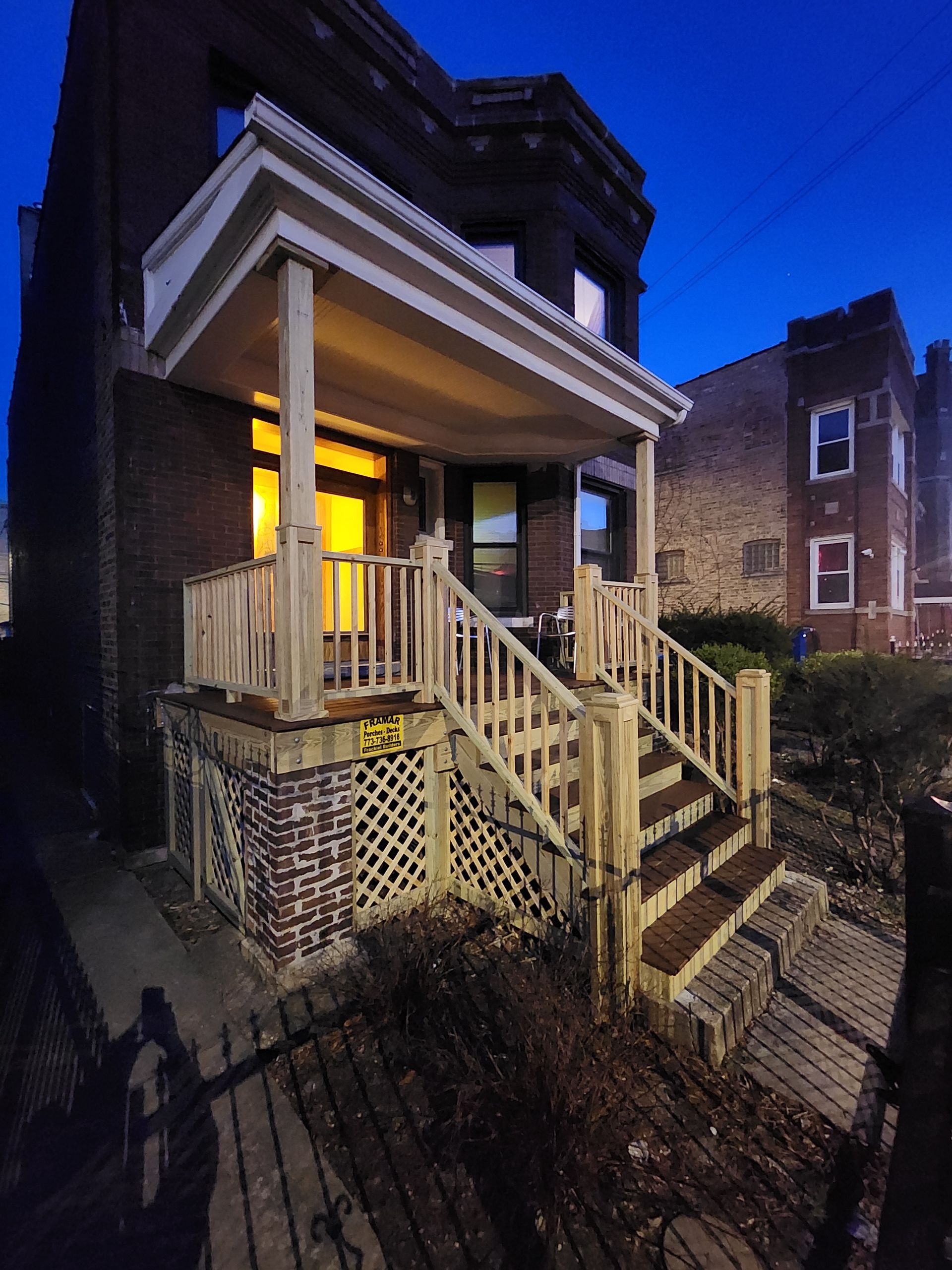 A brick house with a porch and stairs at night.