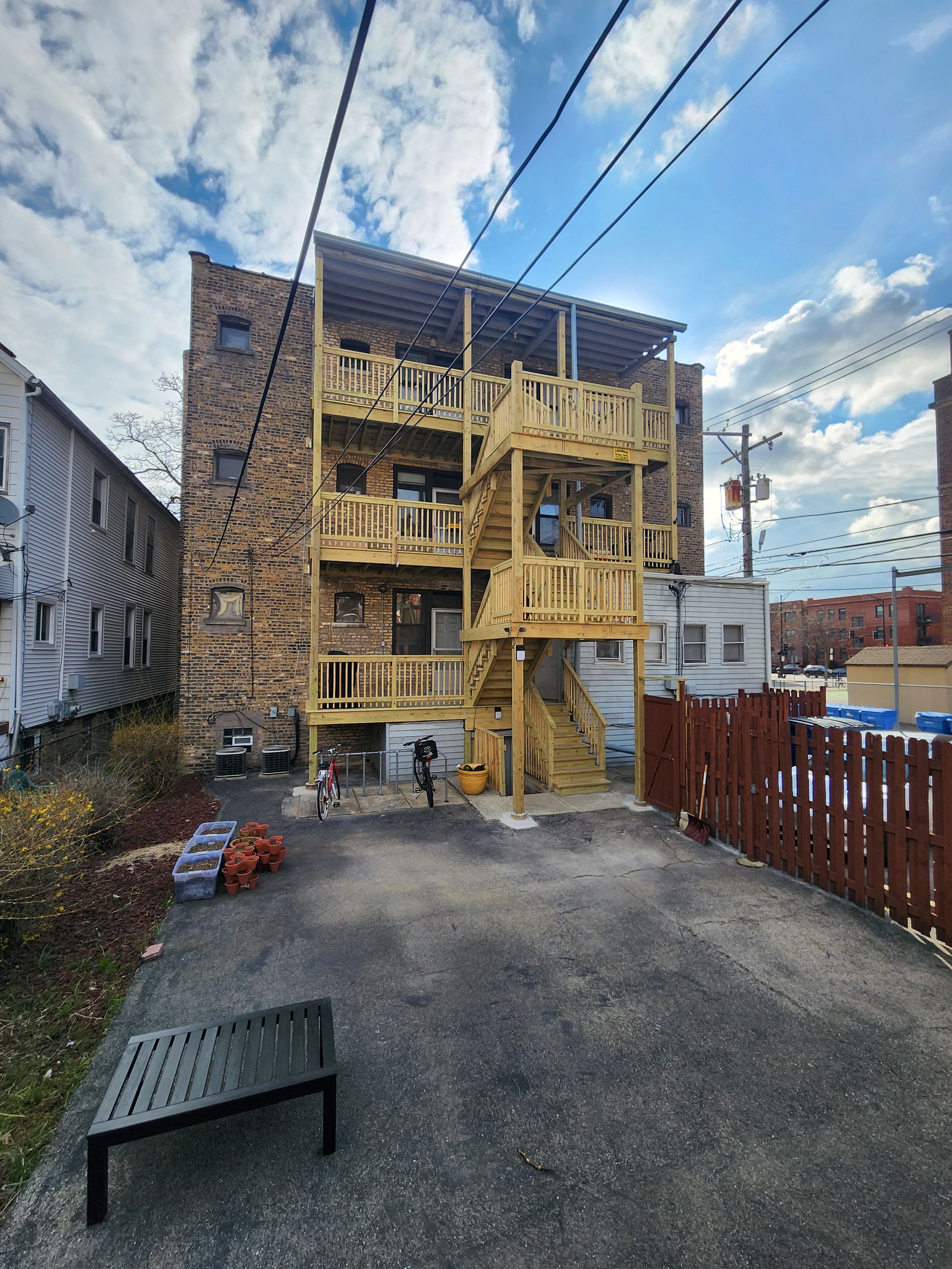 The back of a building with stairs and a bench in front of it.