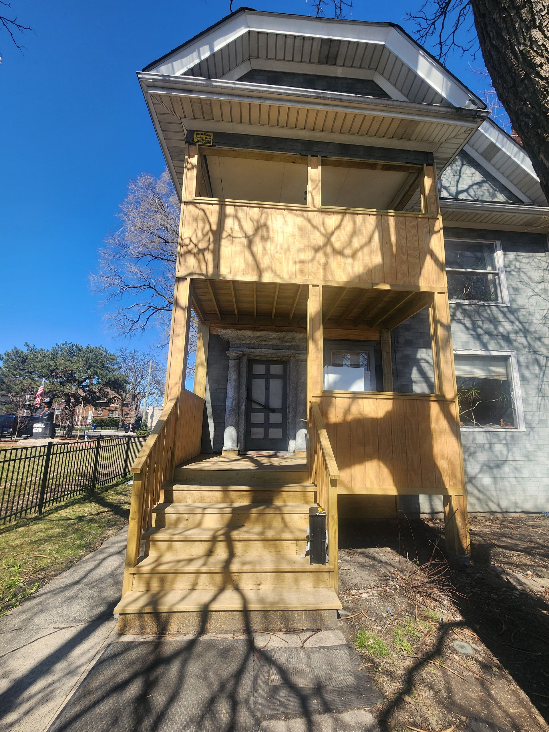 The front of a house with a wooden porch and stairs.