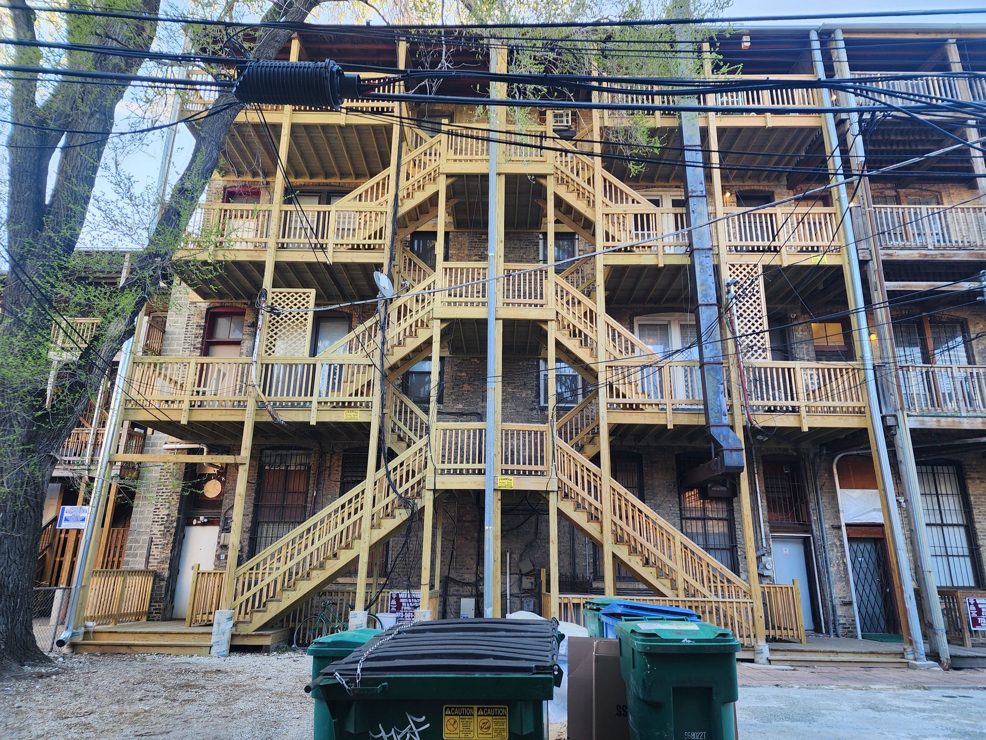 A building with stairs and trash cans in front of it.