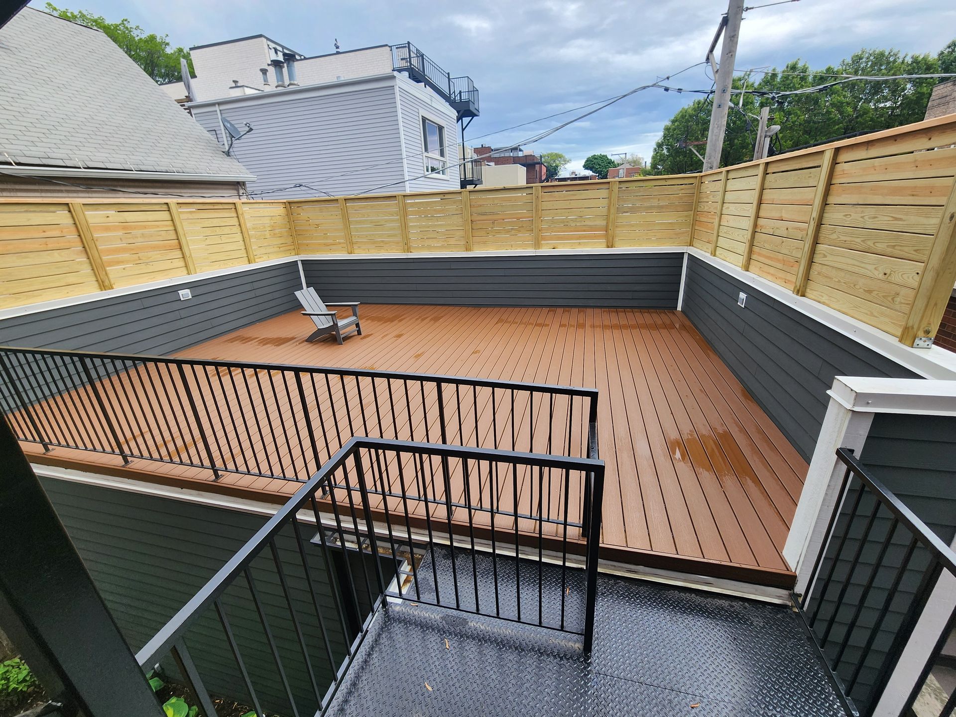 A balcony with a wooden deck and a wooden fence.