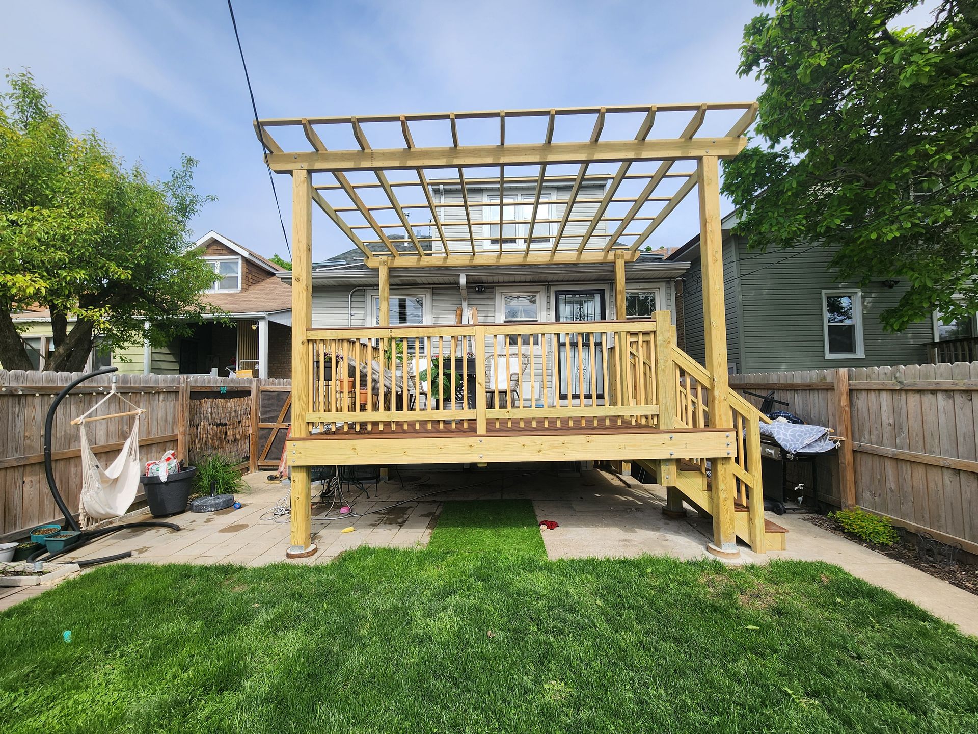 The backyard of a house with a wooden deck and stairs.