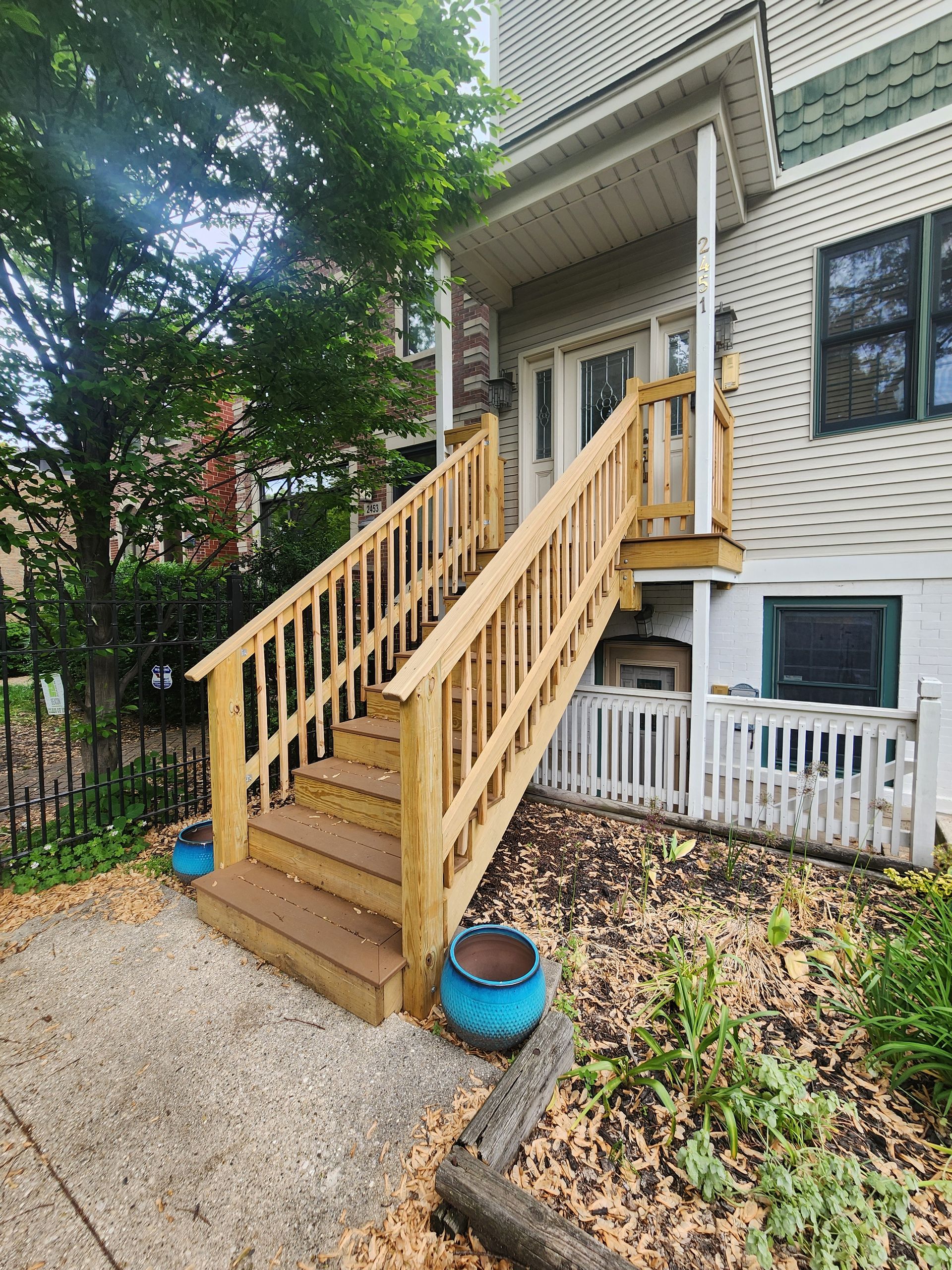 A wooden deck with stairs leading up to the front of a house.