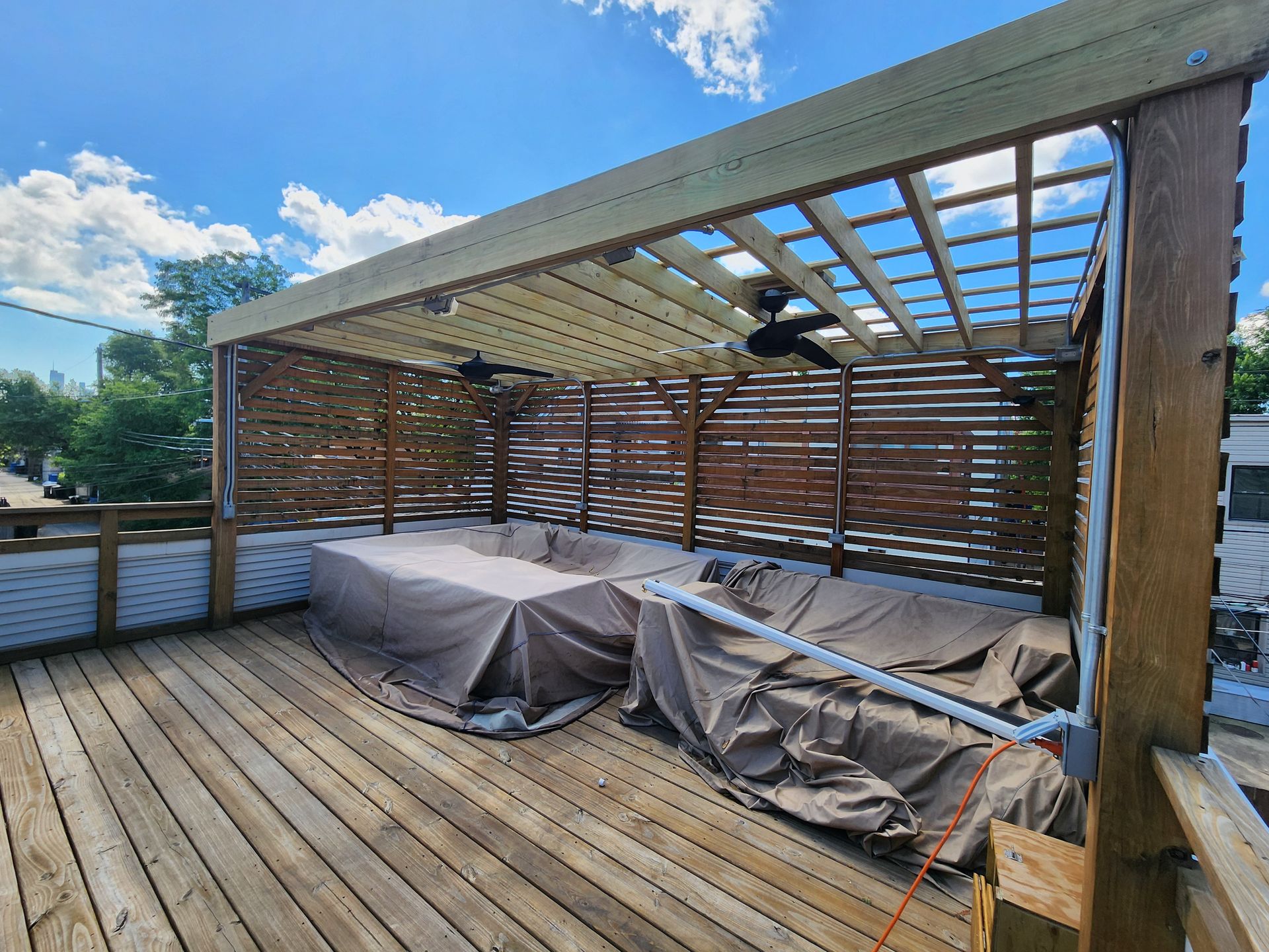 A wooden deck with a pergola and a table underneath it.
