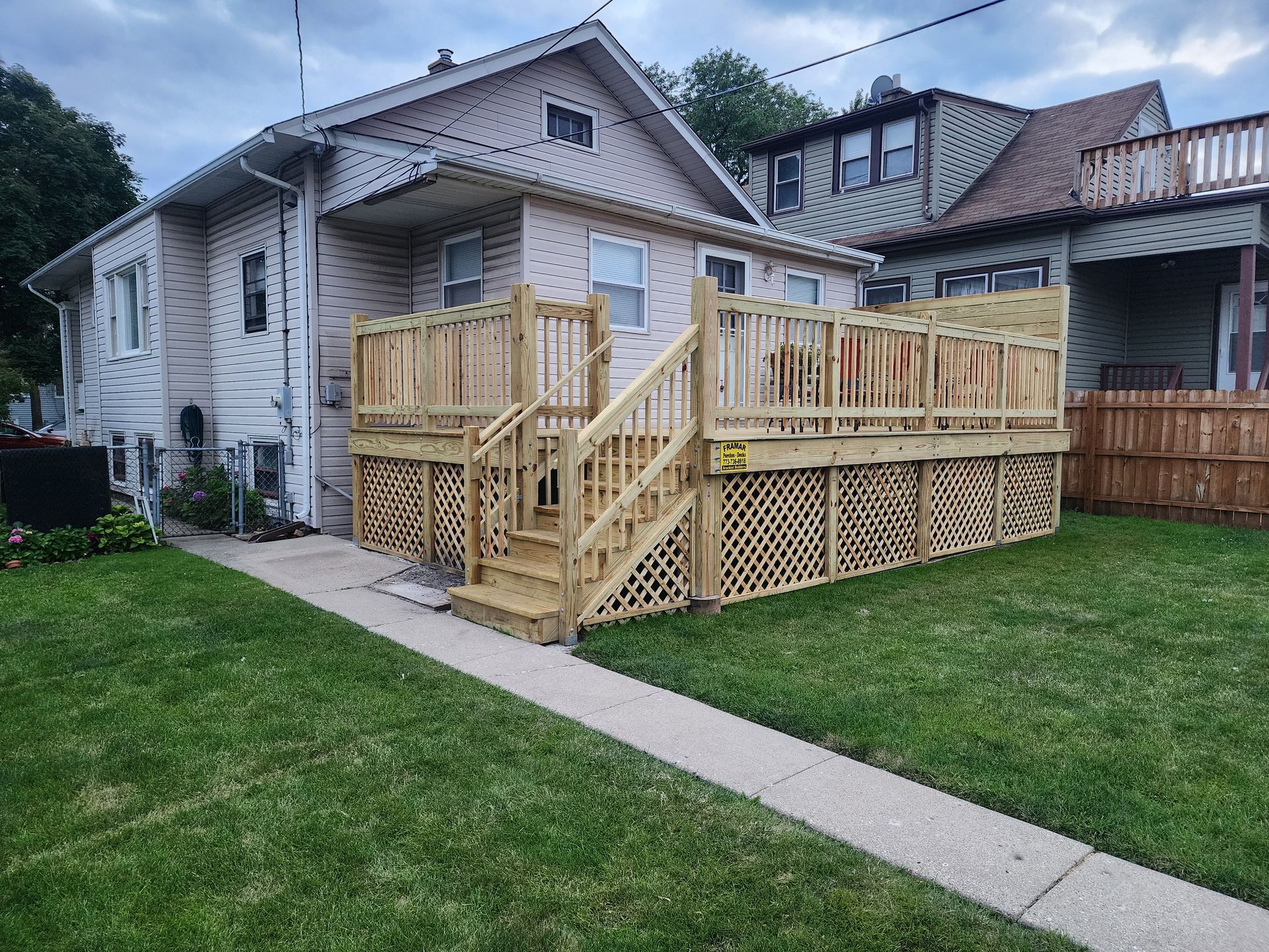 A large wooden deck is sitting in front of a house.