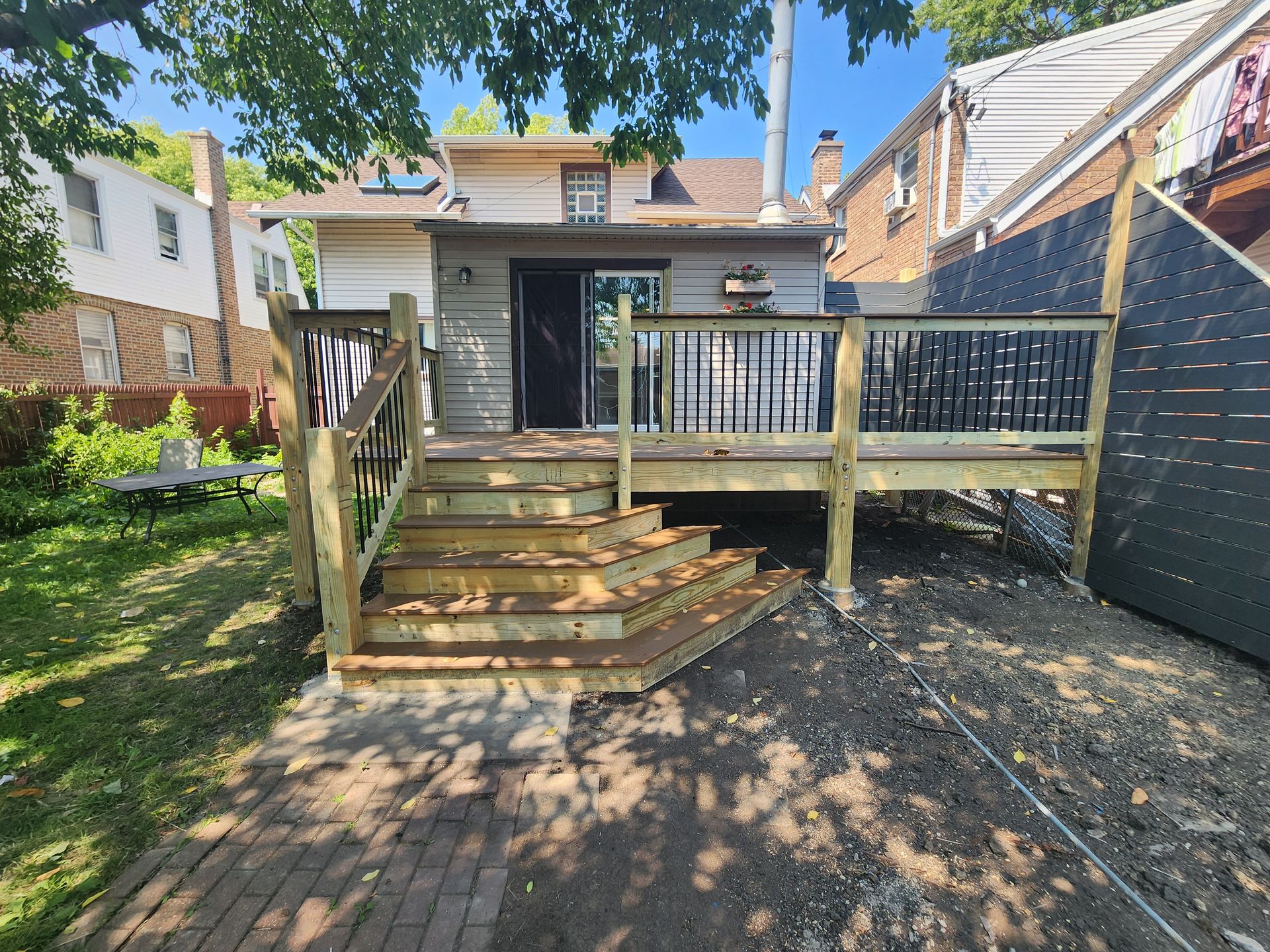 A wooden deck with stairs is in the backyard of a house.