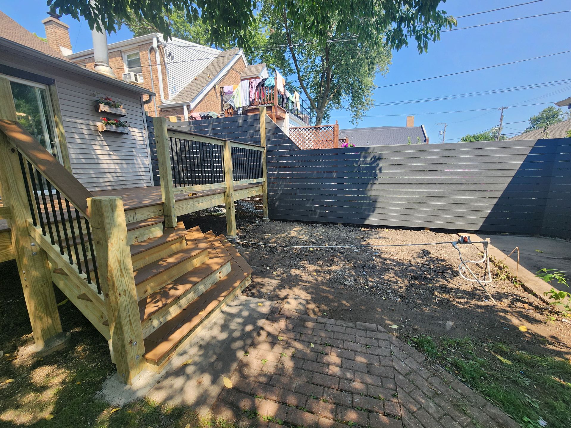 A wooden deck with stairs and a fence in the backyard of a house.