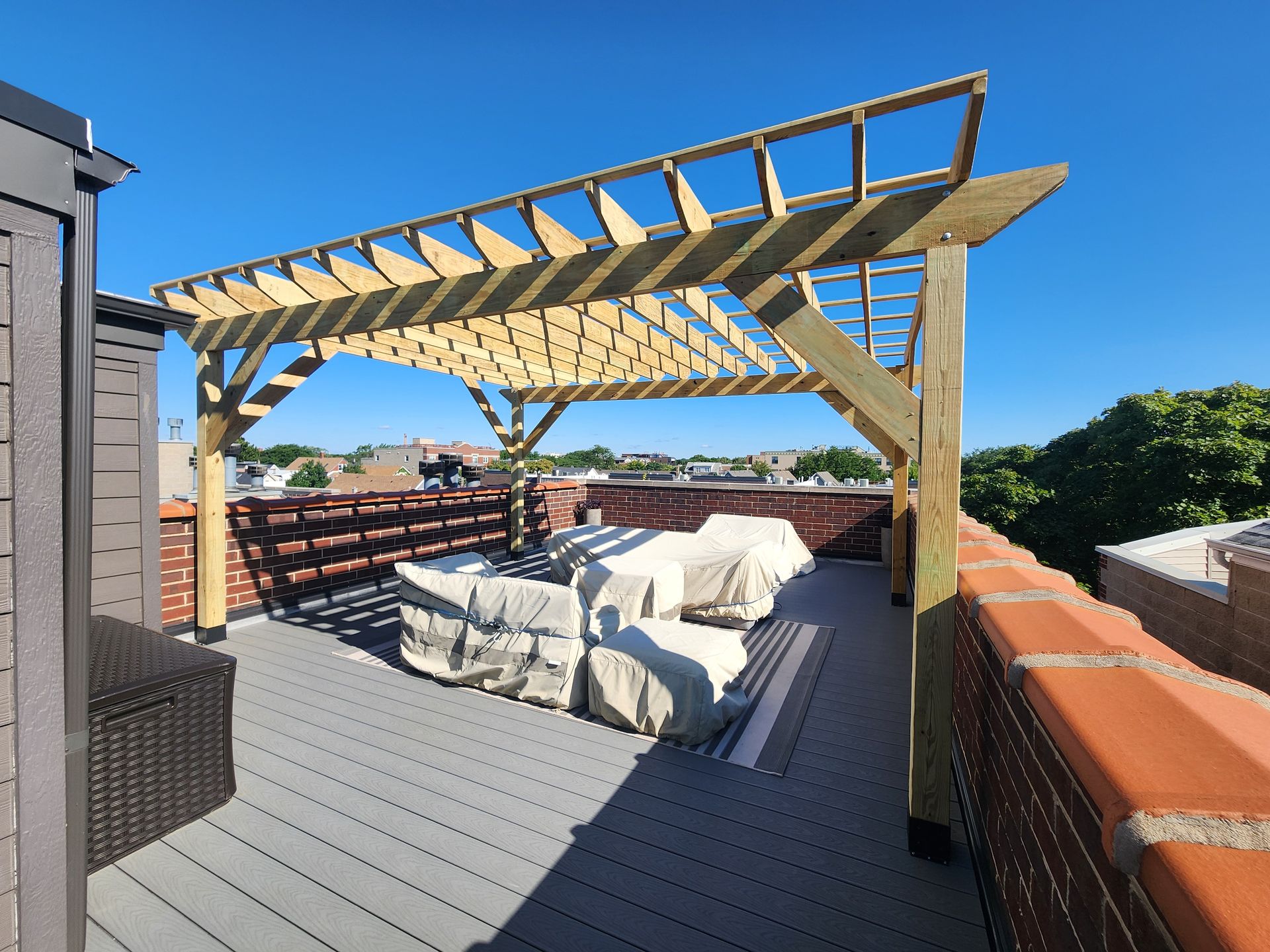 A rooftop deck with a wooden pergola over it.