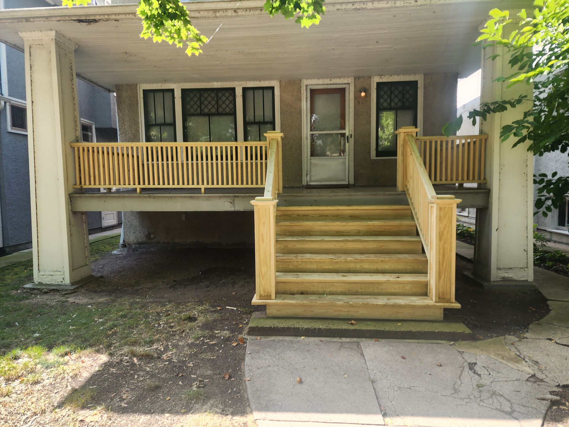The front of a house with a wooden porch and stairs.