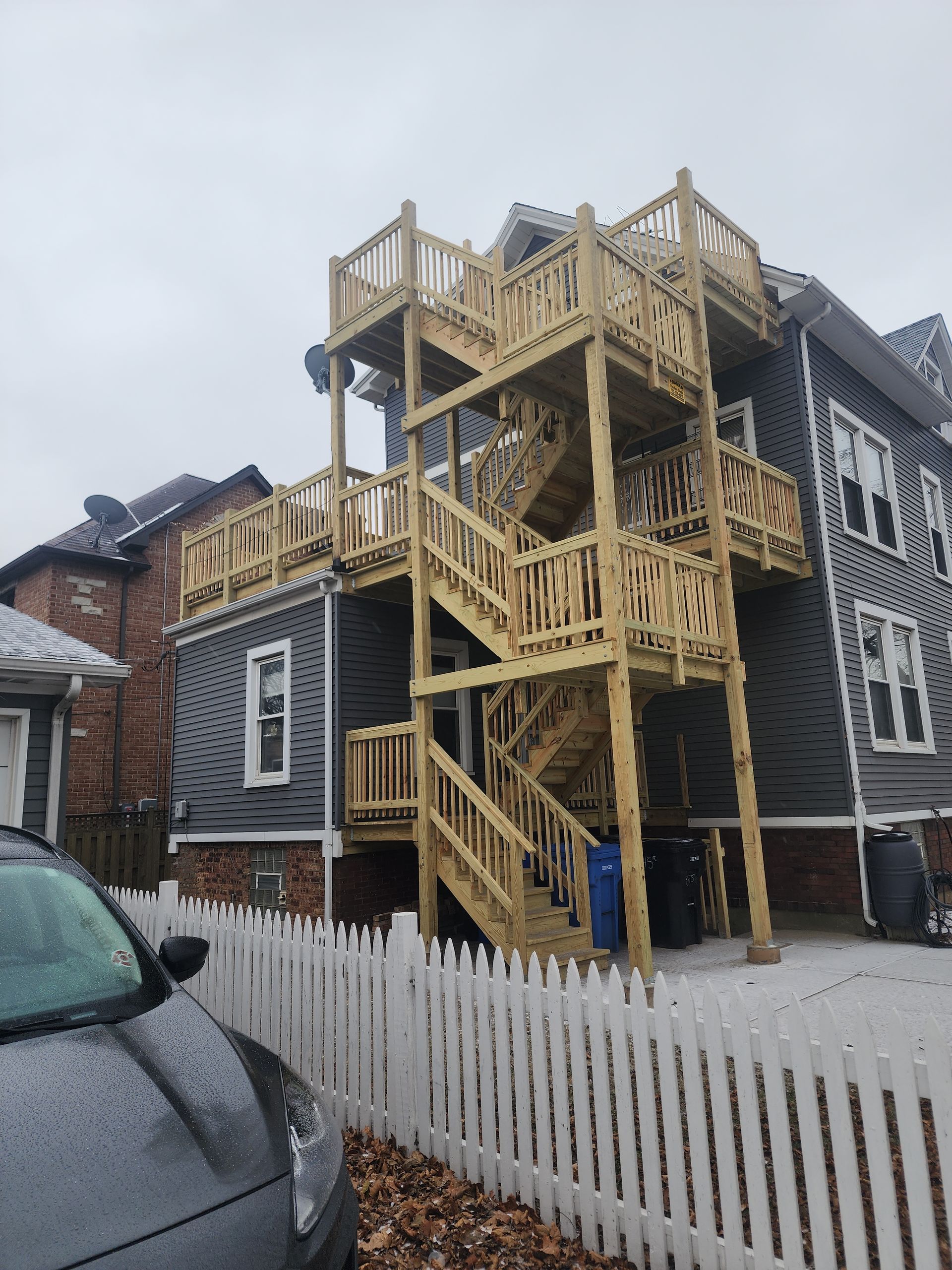 A car is parked in front of a house with wooden stairs.