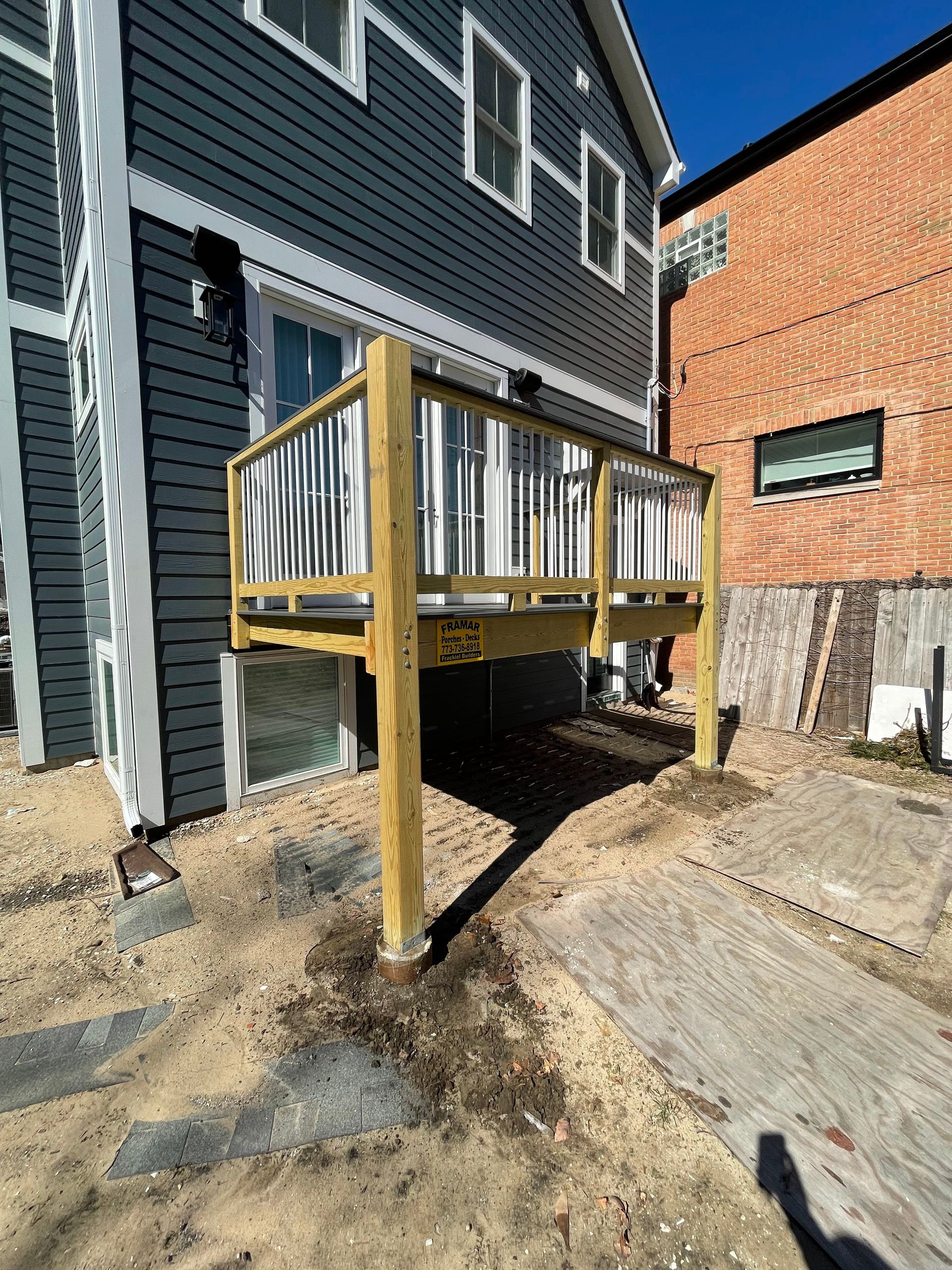 A wooden deck is being built in front of a house.