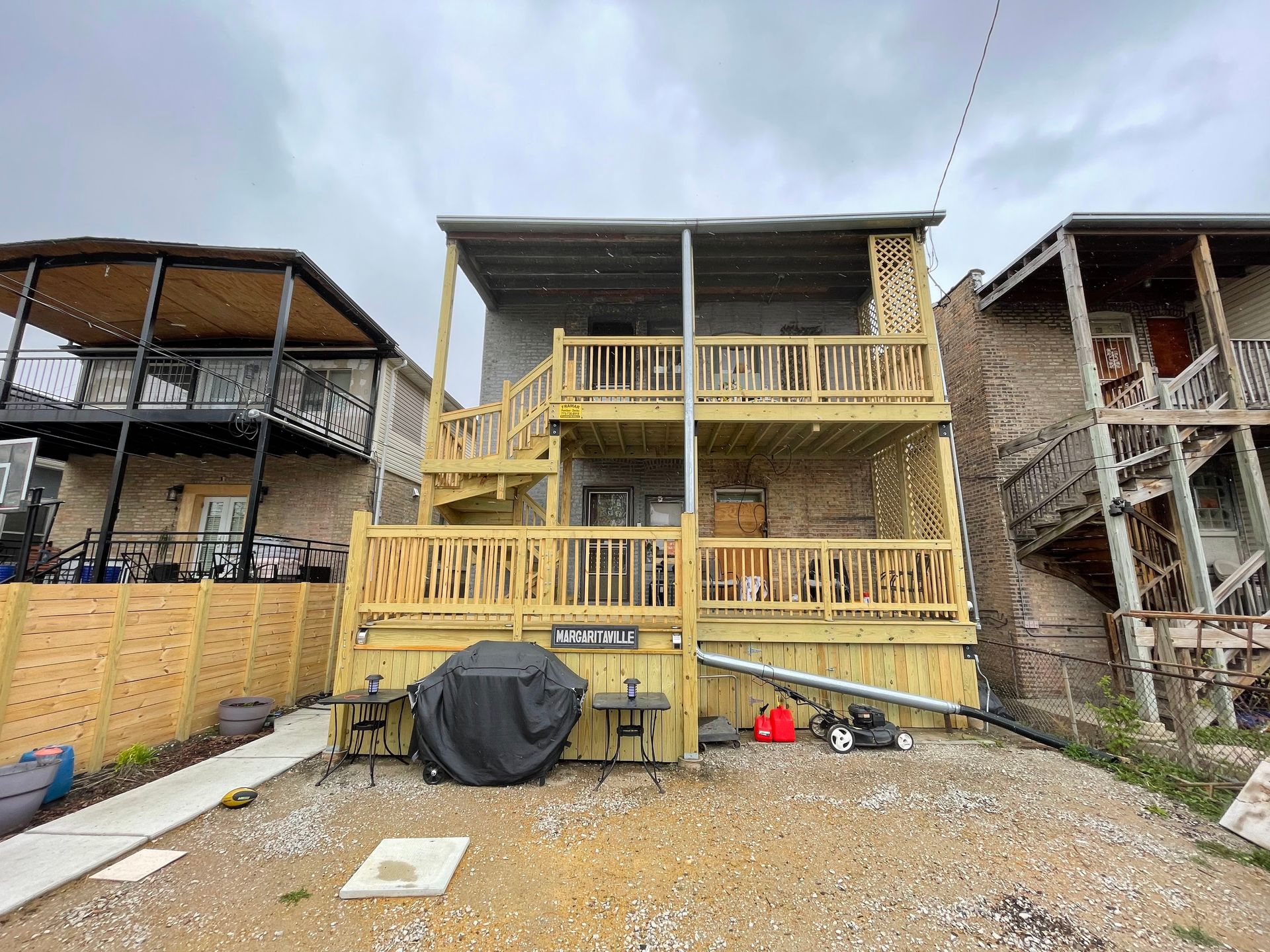 The back of a house with a wooden deck and stairs.