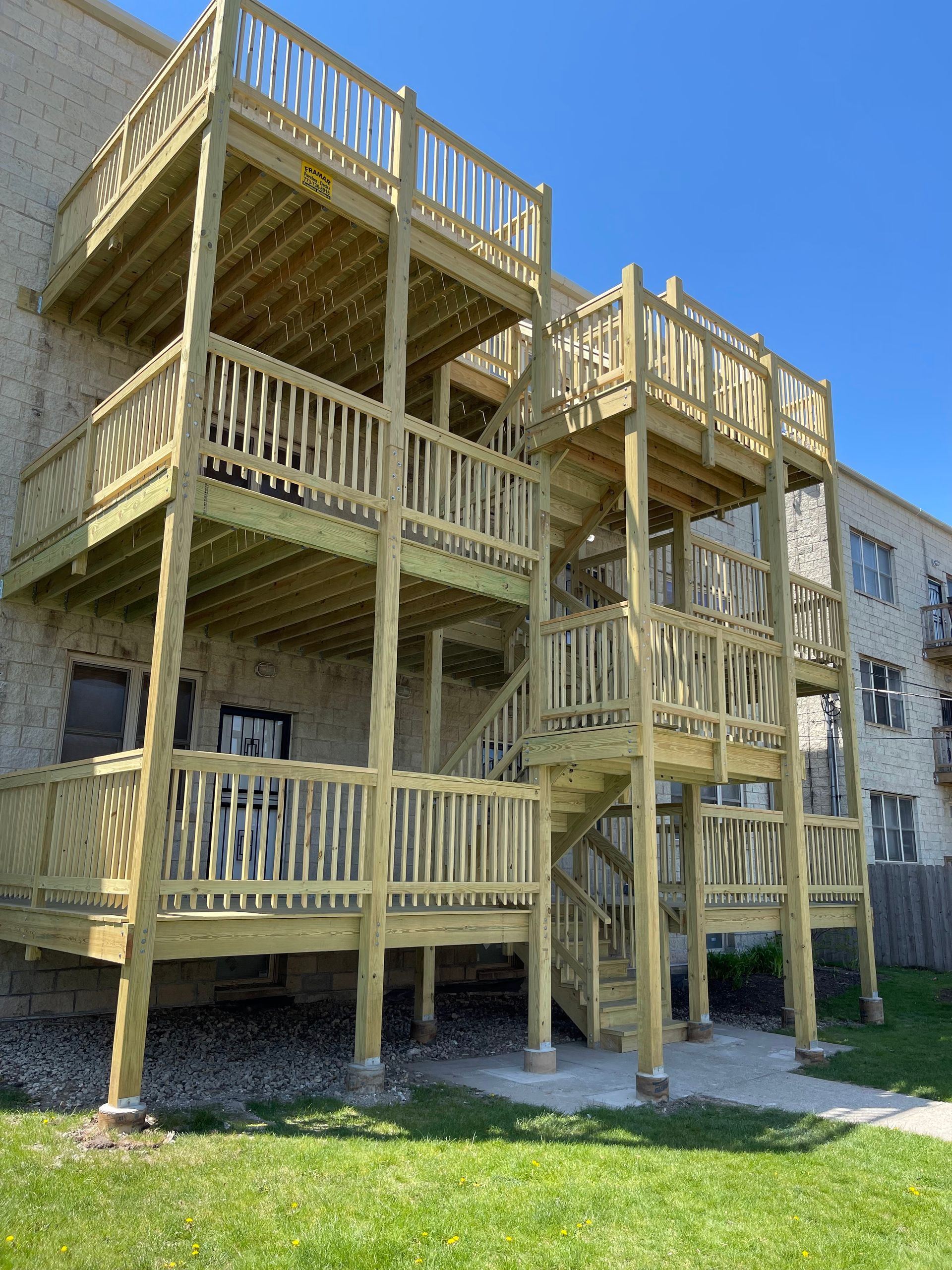 A large wooden deck with stairs is in front of a building.