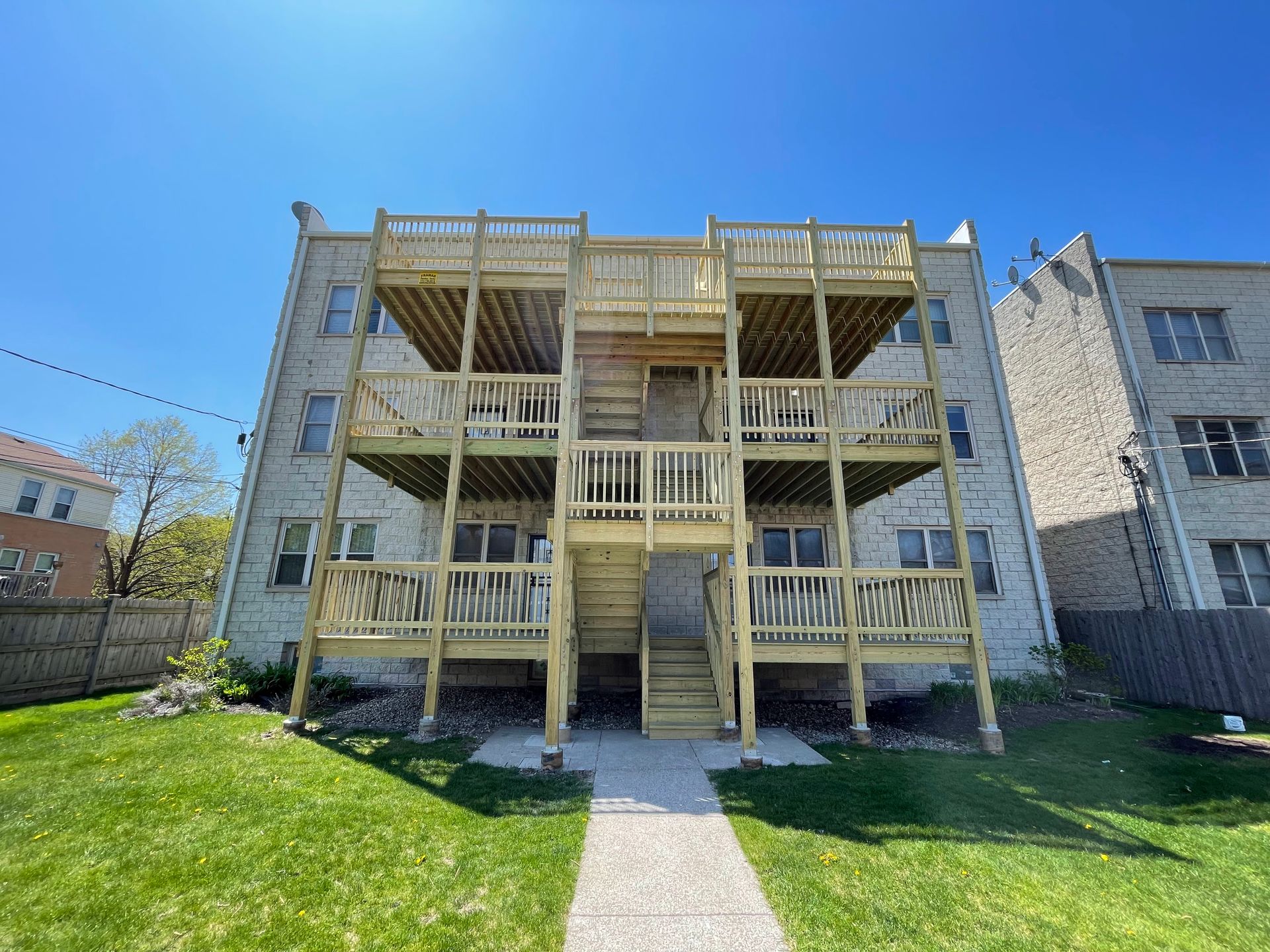 The back of a building with a wooden deck and stairs.
