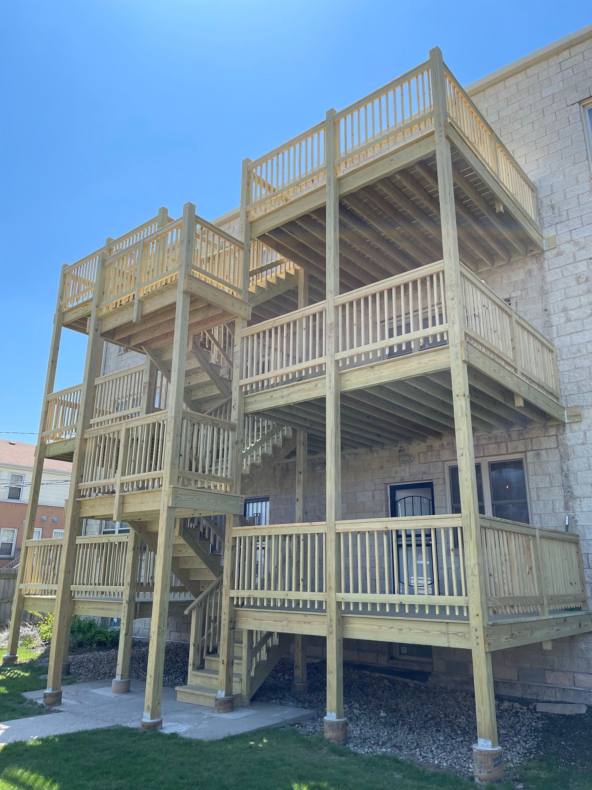 A large wooden deck with stairs on the side of a building.