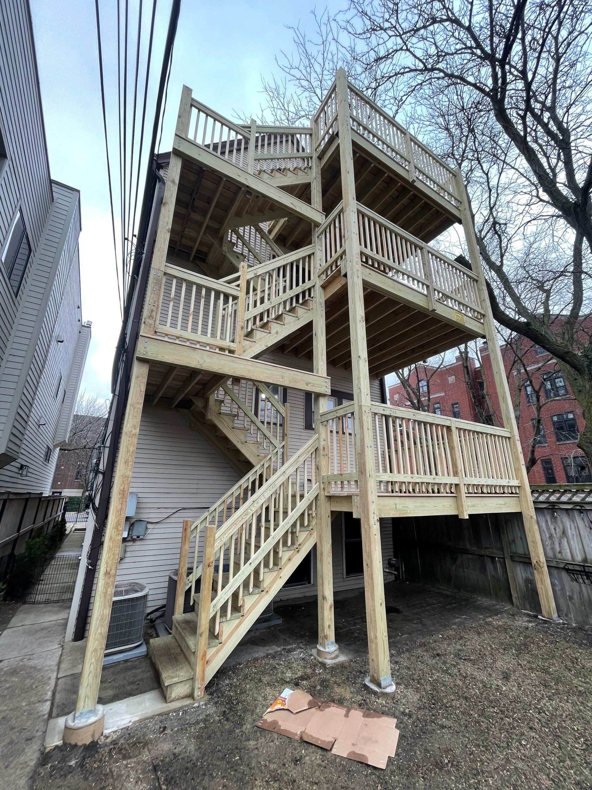 A wooden deck with stairs leading up to it is being built on the side of a house.