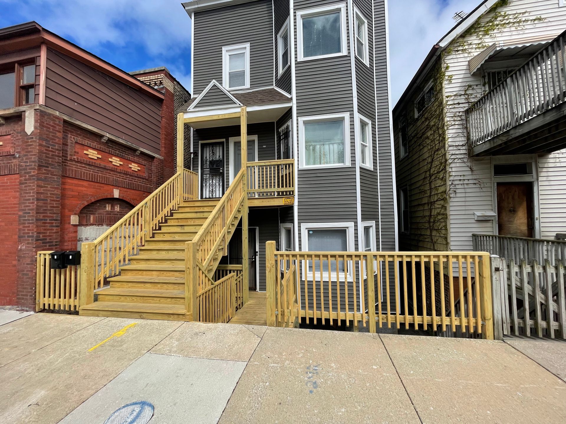 A house with stairs leading up to the second floor and a wooden deck.