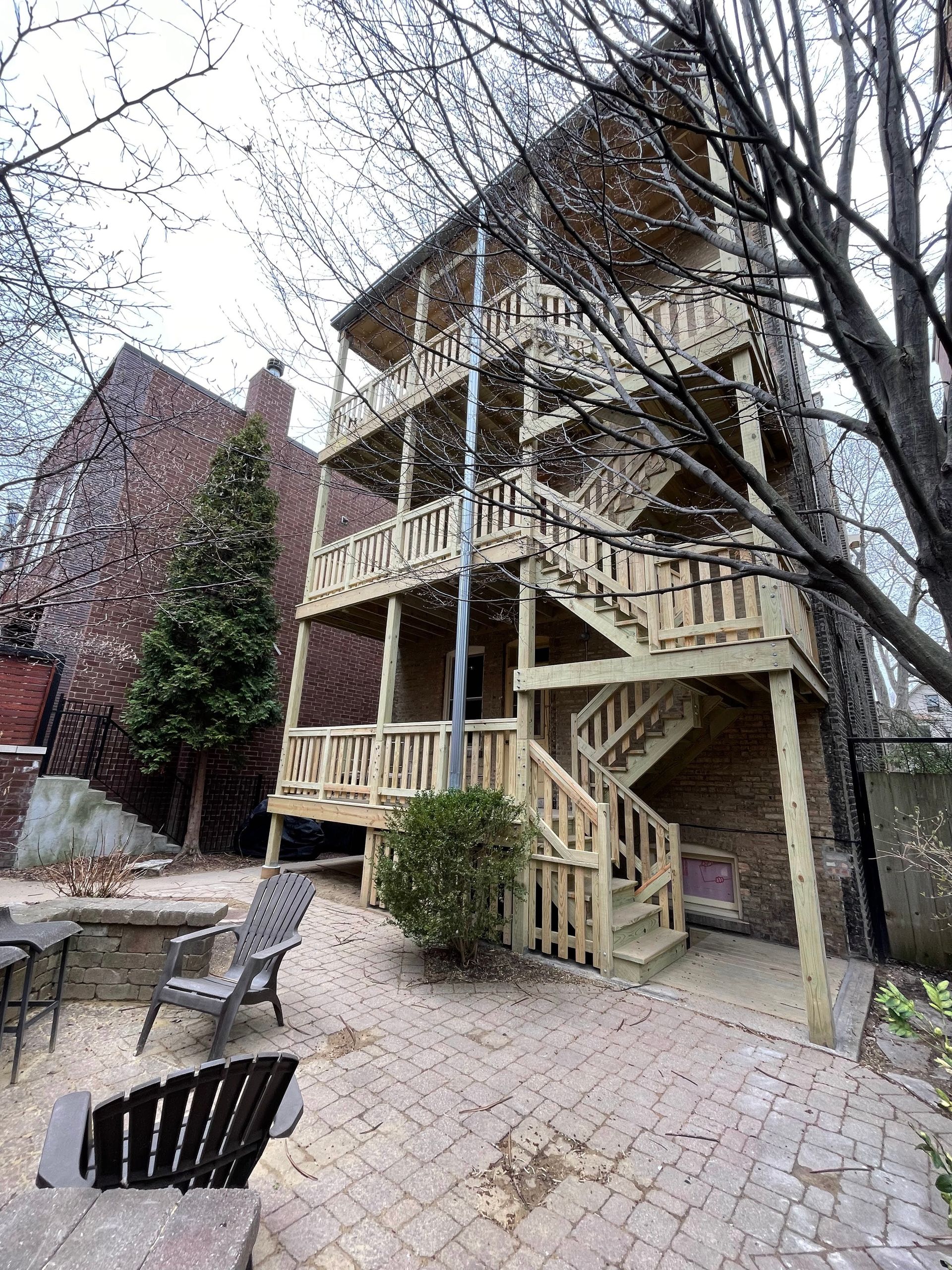 A large house with a wooden deck and stairs in the backyard.