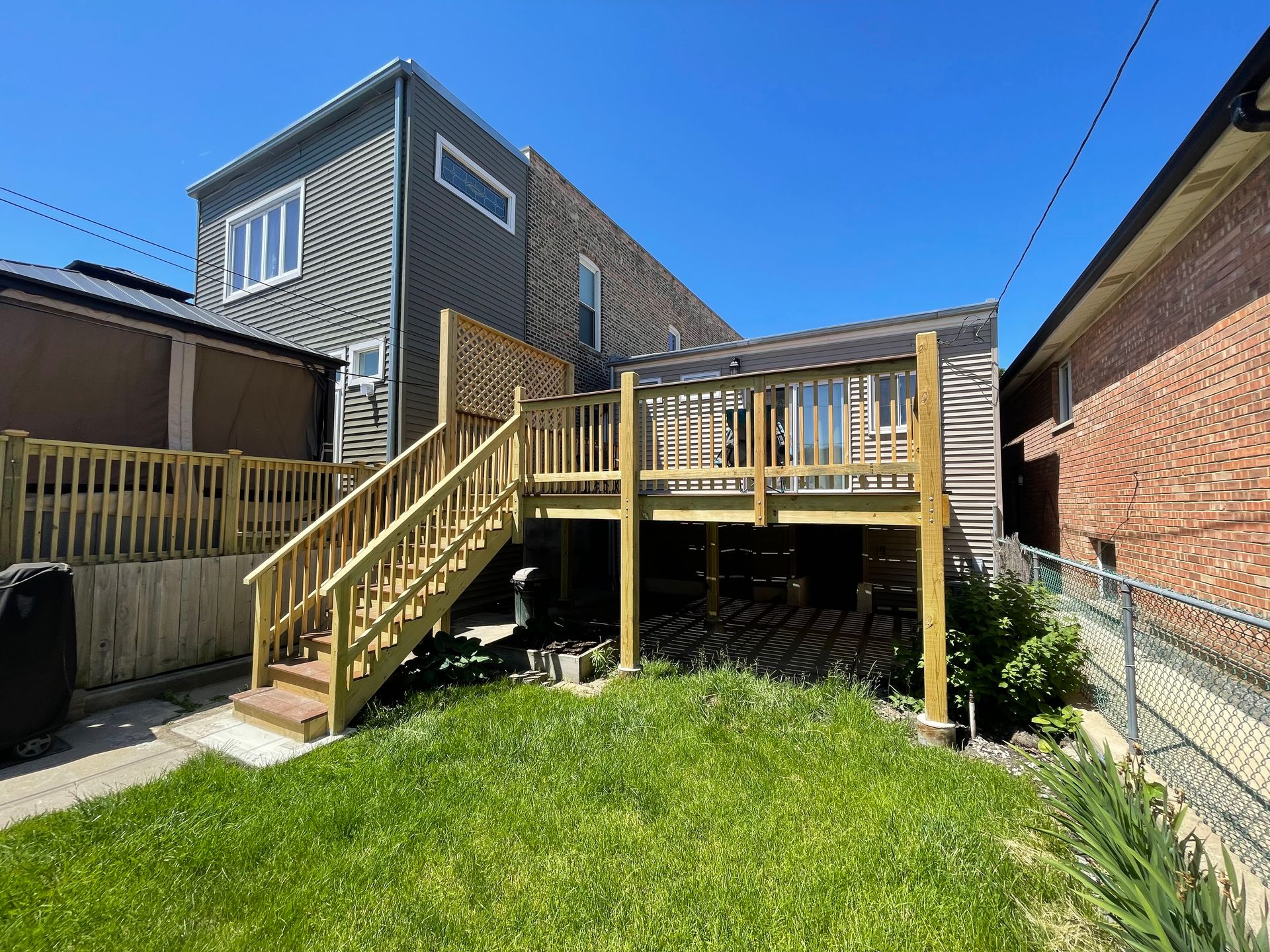The backyard of a house with a wooden deck and stairs.