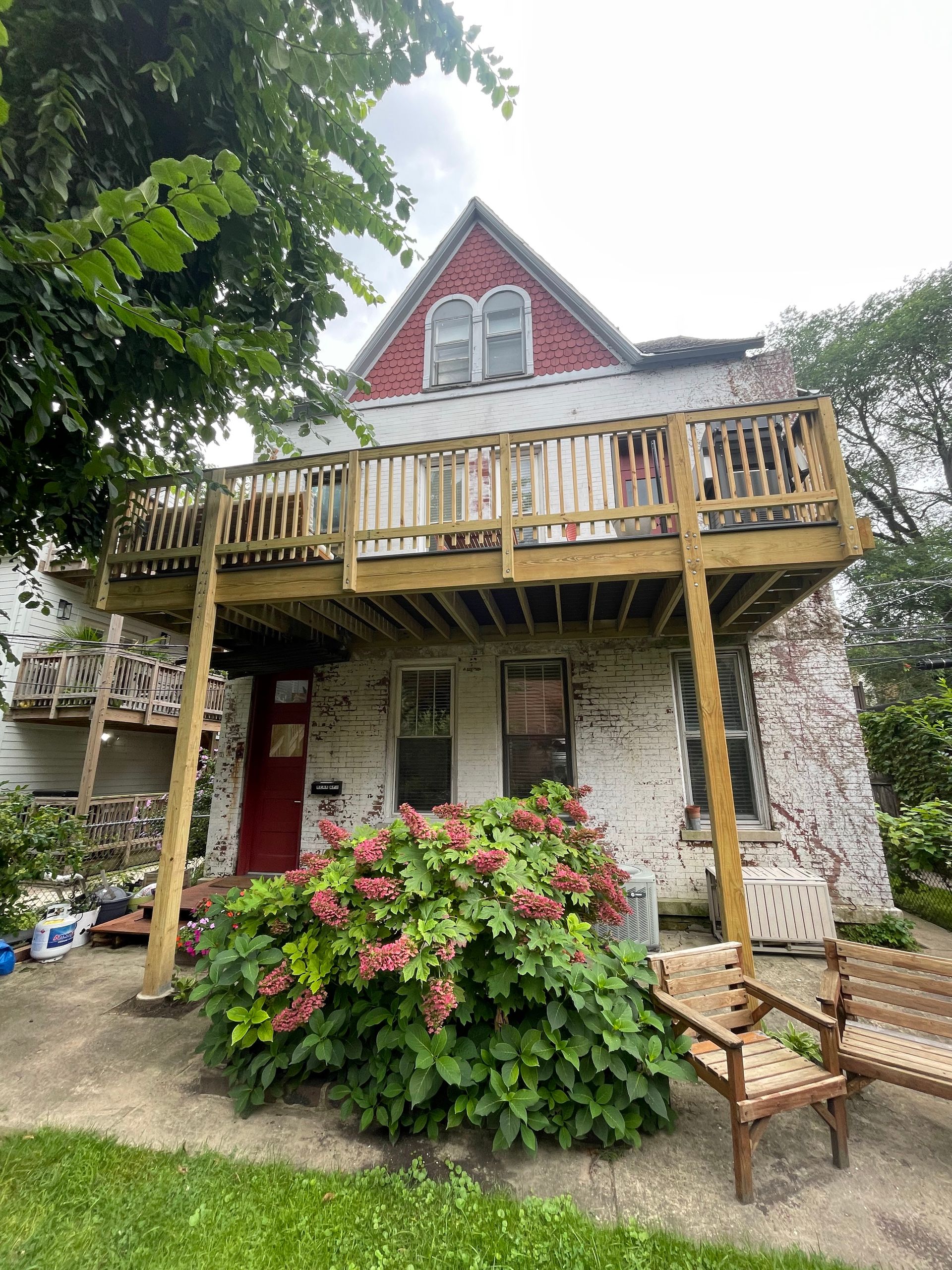 A white house with a red roof and a wooden deck.
