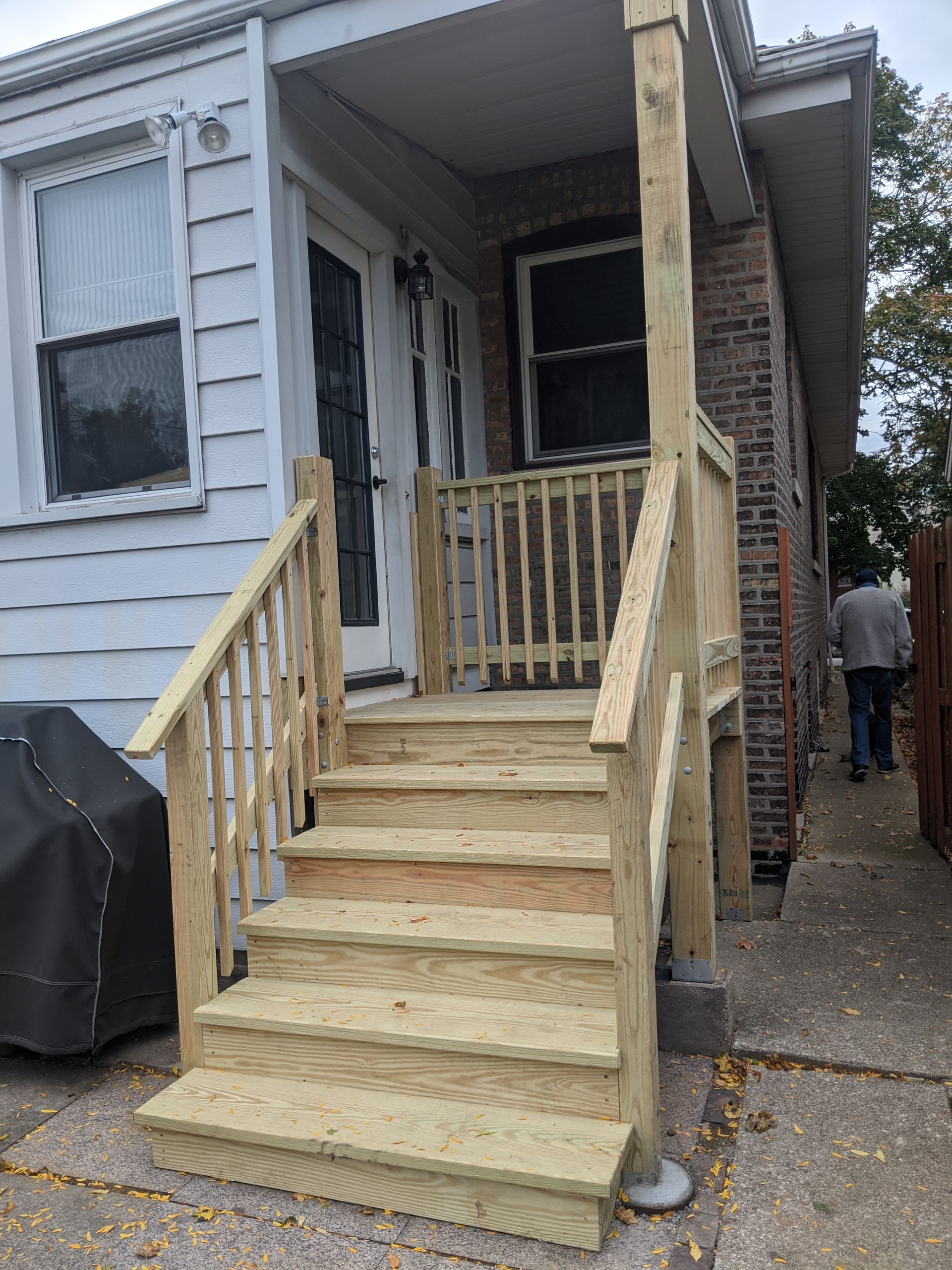A wooden porch with stairs and a railing is in front of a house.