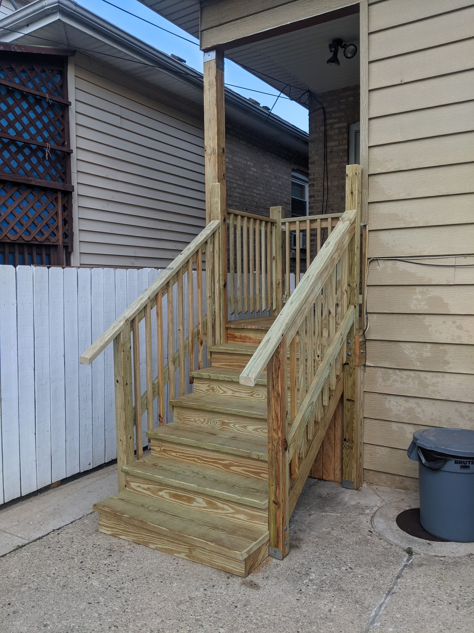 A wooden deck with stairs leading up to the front door of a house.