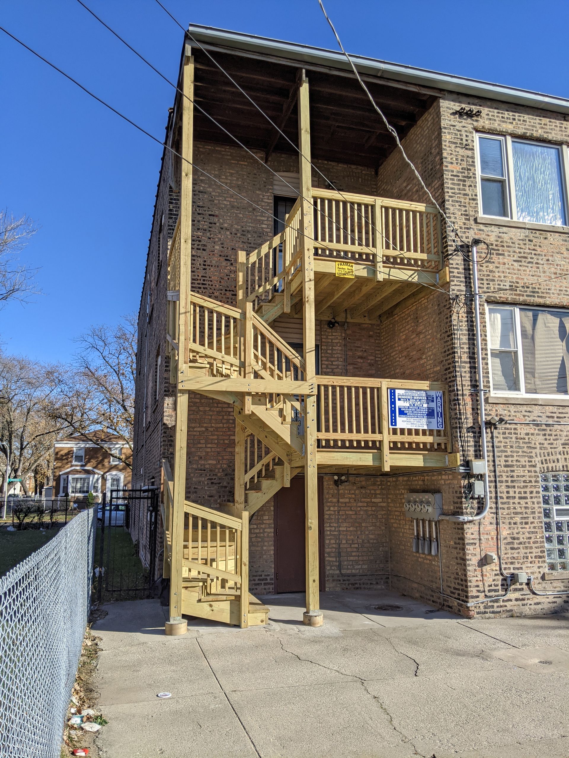 A brick building with a wooden fire escape on the second floor.