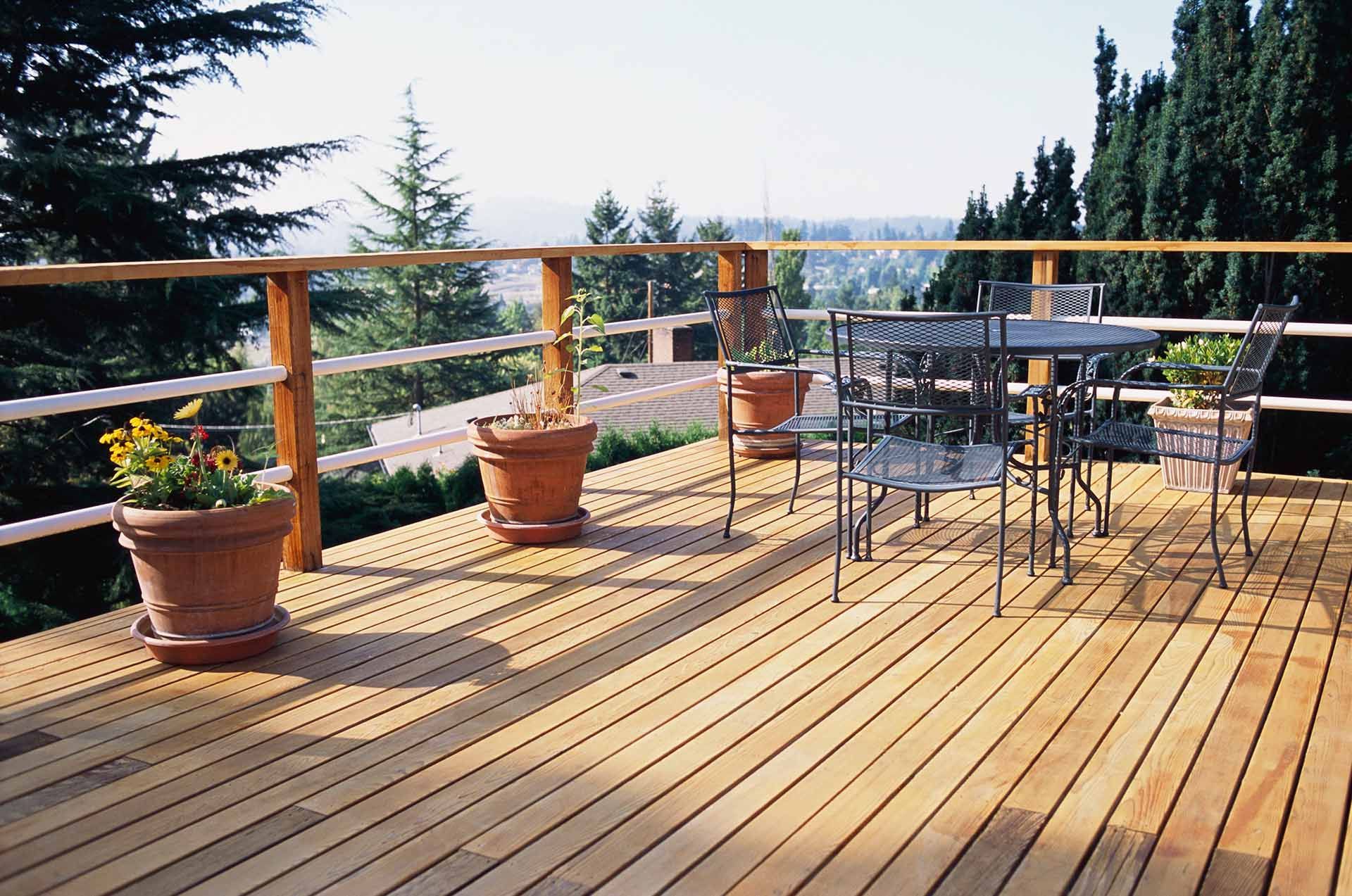 Spacious wooden deck with potted plants and outdoor dining furniture. Spacious wooden deck with potted plants and outdoor dining furniture.