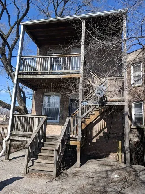 A house with stairs leading up to the second floor and a balcony.