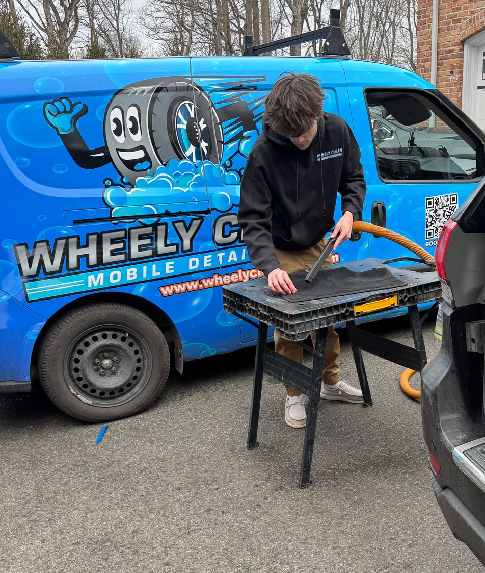 Blue van with a ladder parked inside a car wash bay, with