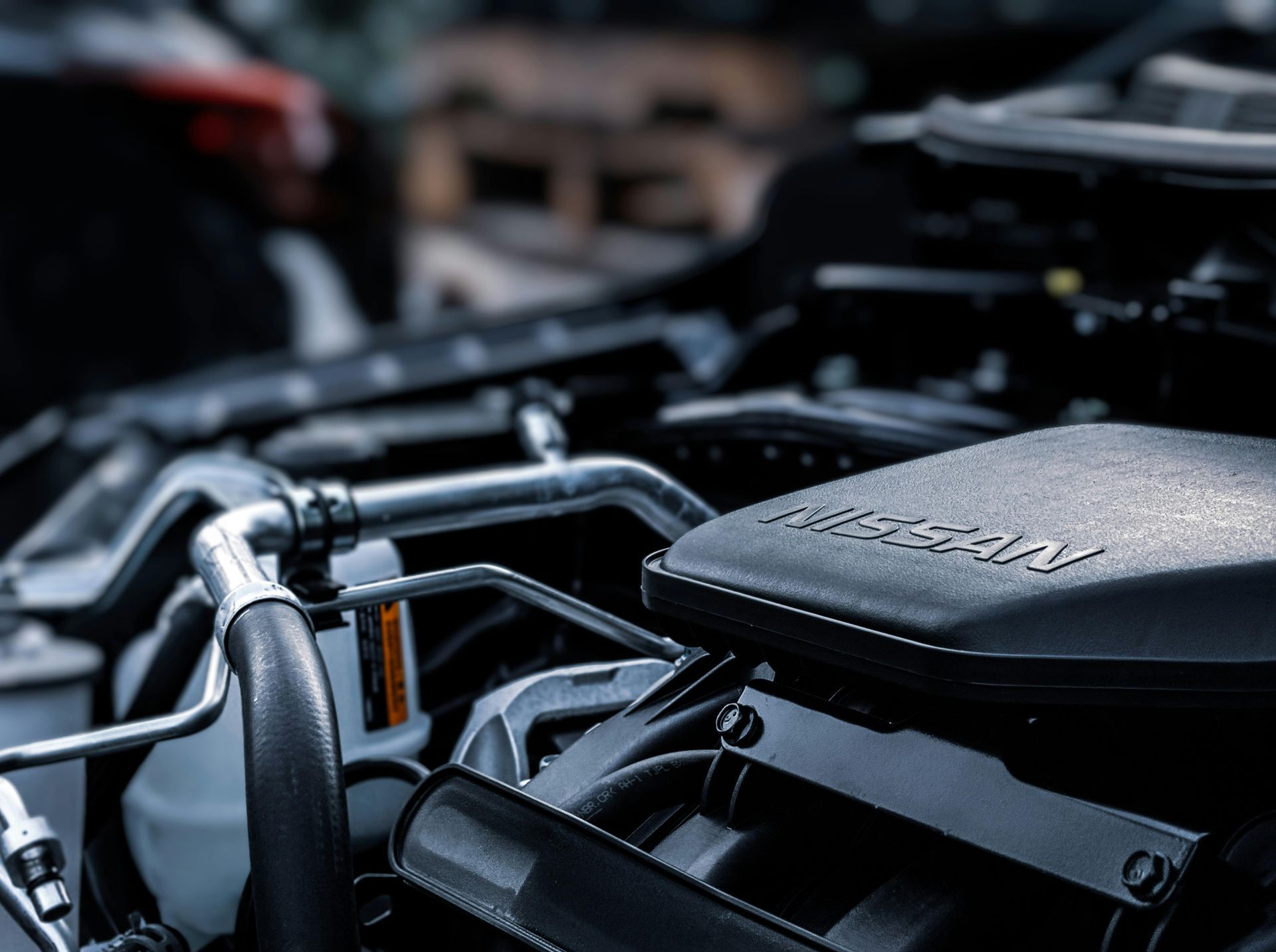 Close-up of a black car engine with various tubes and a cover labeled