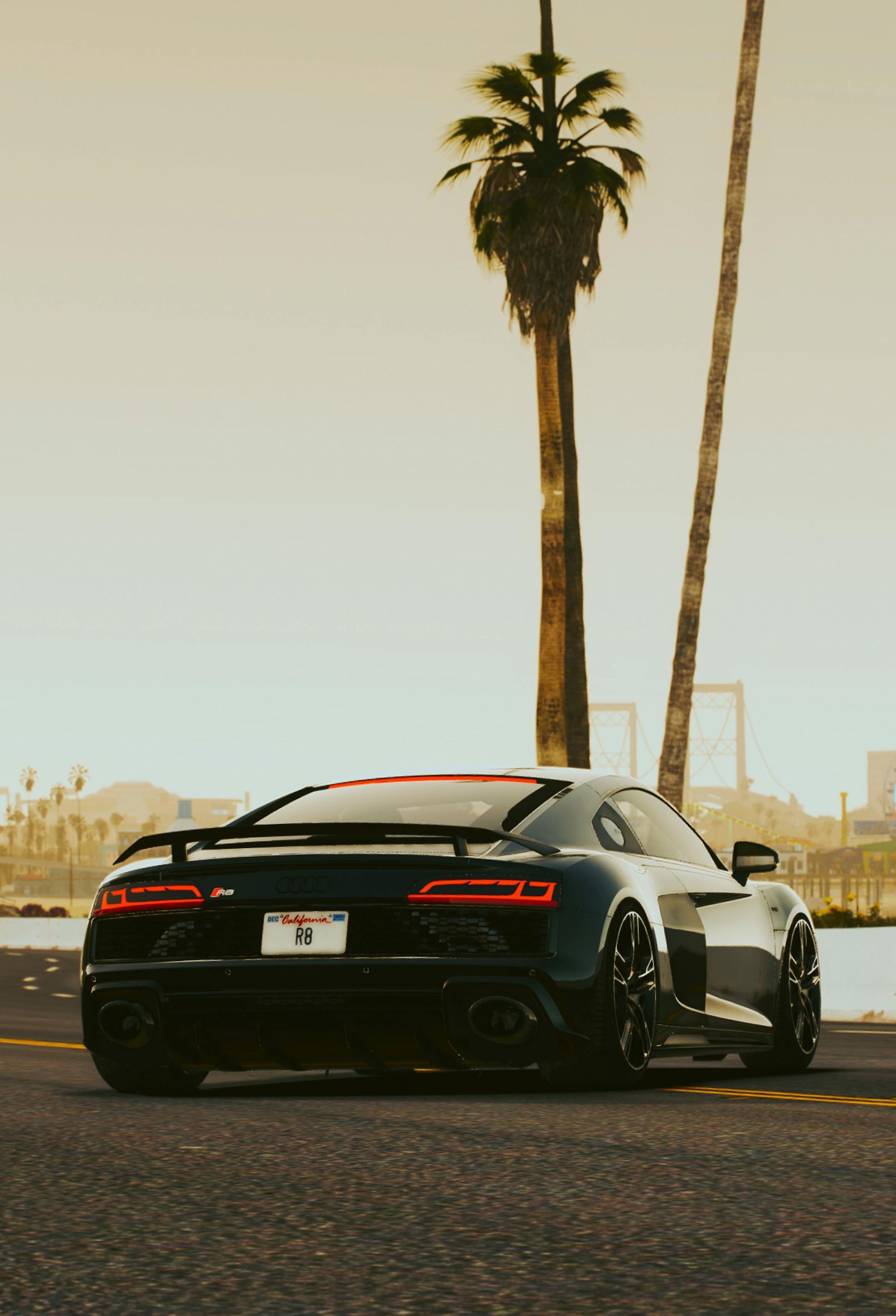 Black sports car parked by palm trees at sunset, with a city skyline in the background