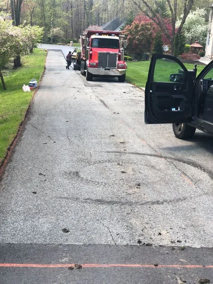 Asphalt driveway with truck, workers, and open vehicle door.