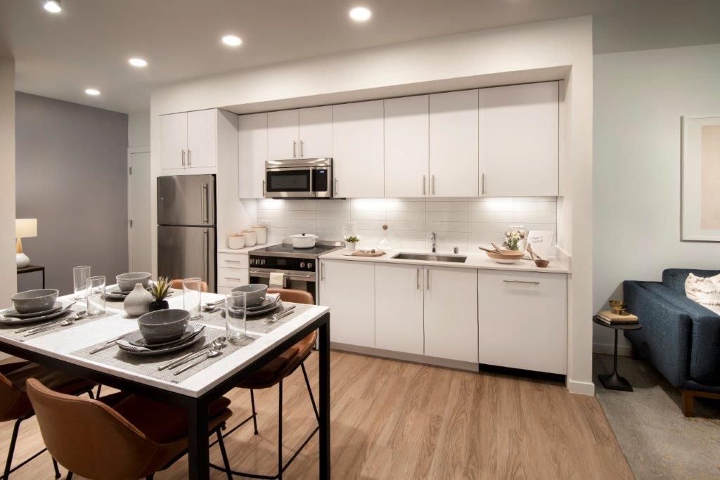 Open-concept kitchen with white cabinets, stainless steel appliances, and a dining table.