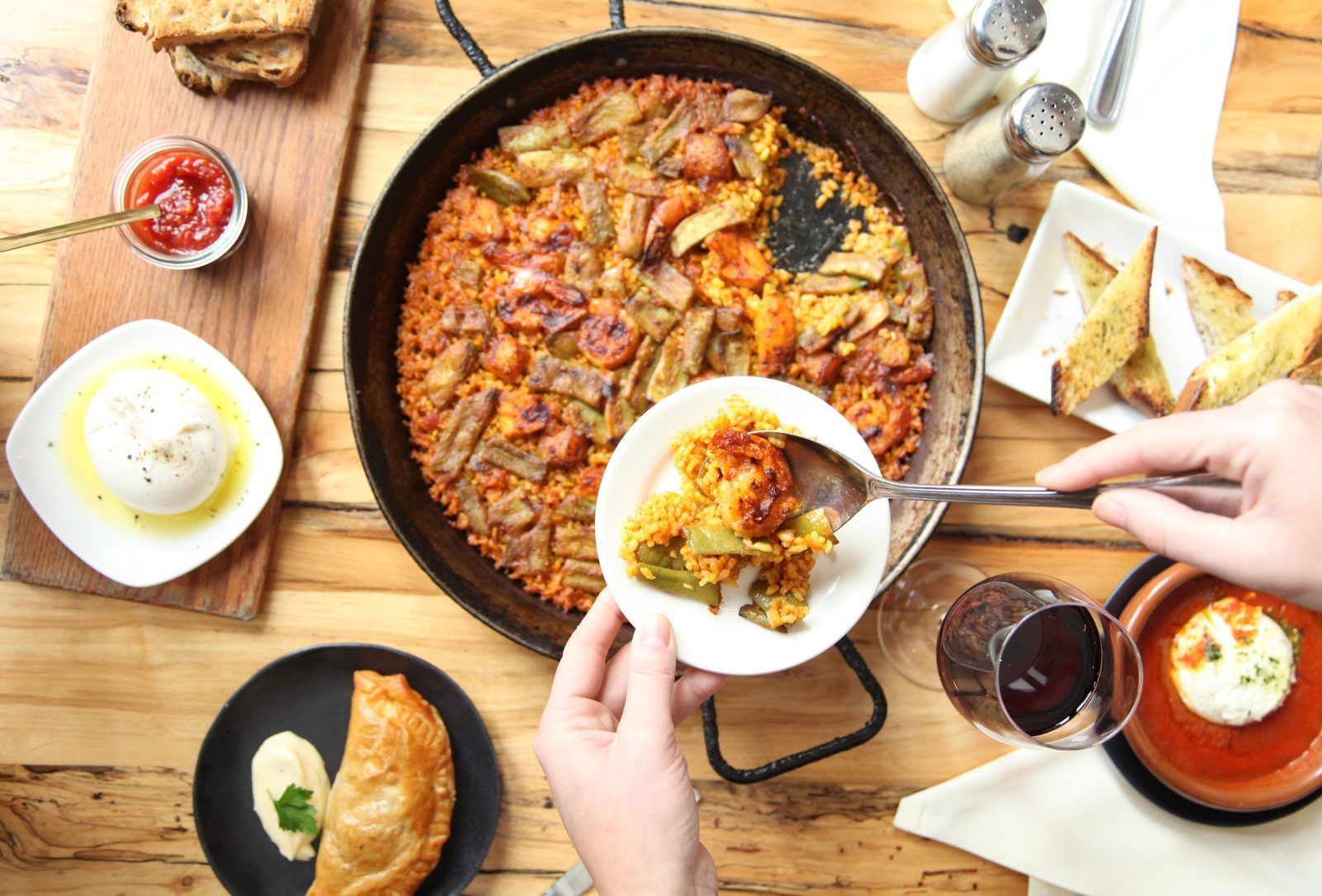 A person is holding a plate of food in front of a pan of food.