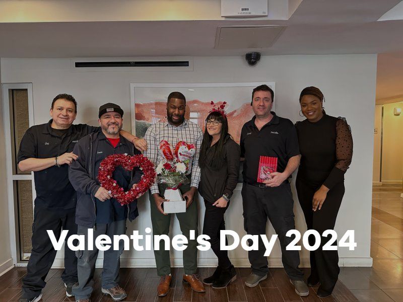 Group posing indoors with heart-shaped decorations and “Valentine’s Day 2024” text overlay