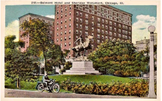 A man is riding a motorcycle in front of a large building