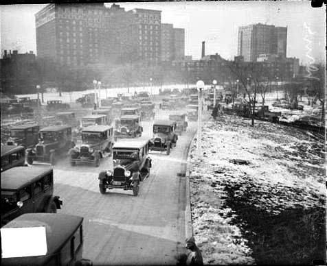 A black and white photo of cars driving down a street