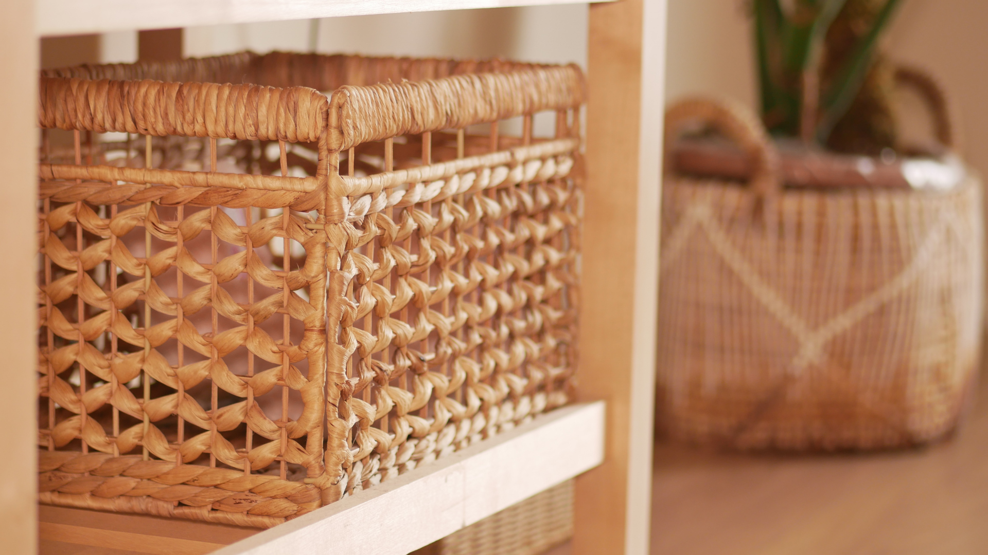 Woven wicker storage baskets on a shelf, one in focus and another blurred in the background.