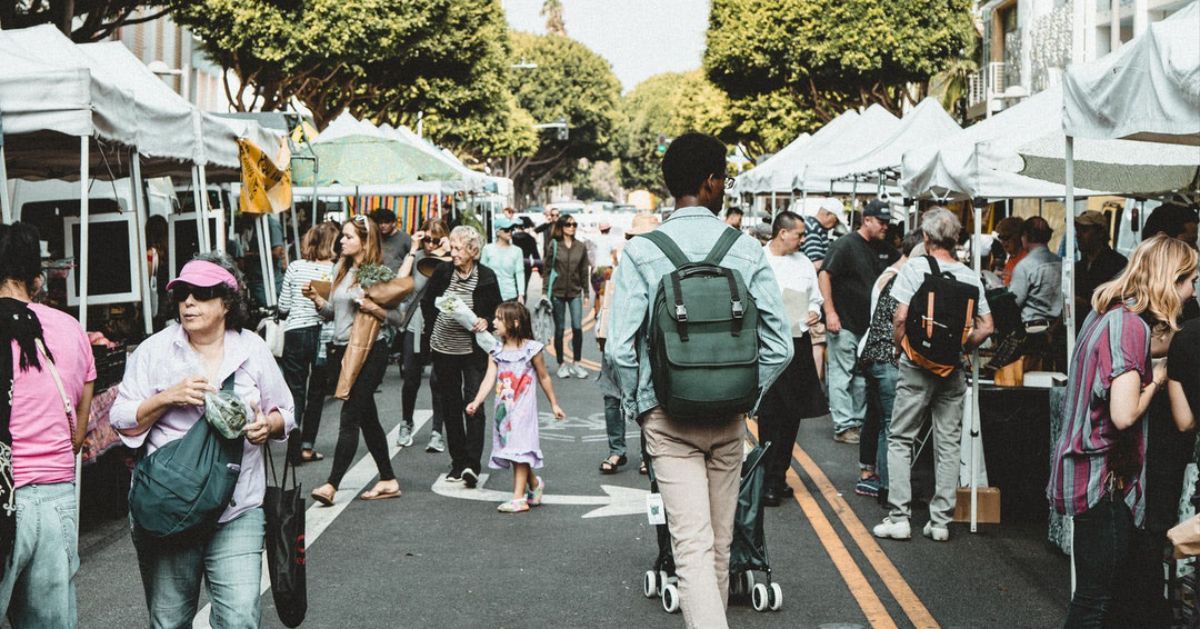 A crowd of people are walking down a street at a market.
