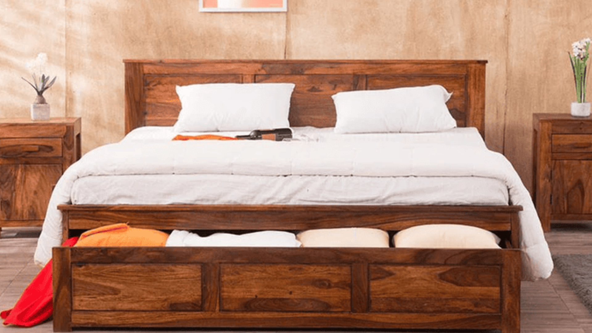 Wooden bed with white bedding and open storage drawers in a warm-toned bedroom