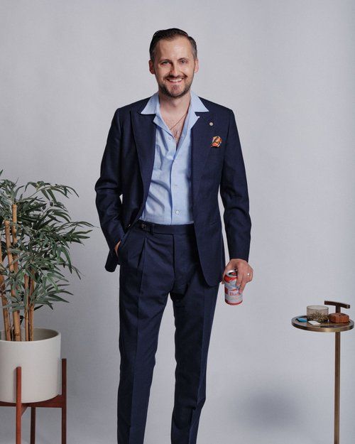 A man in a suit is holding a can of soda
