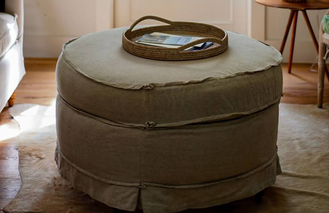 Round ottomon in a living room with a woven tray